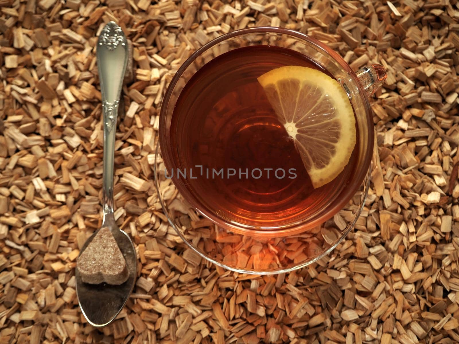 Black tea with lemon in a transparent cup on a wooden tray.