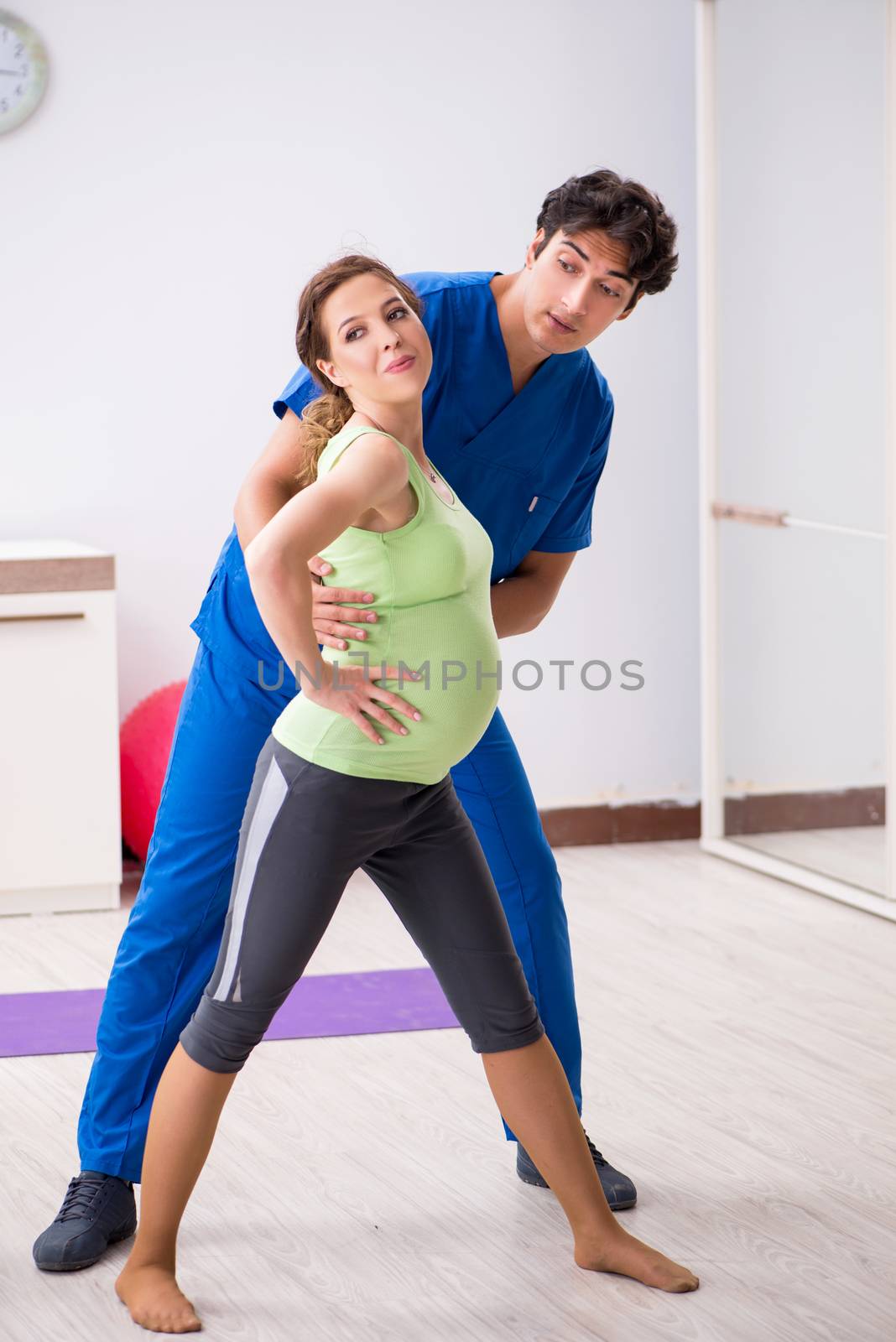 Pregnant woman doing physical exercies with instructor