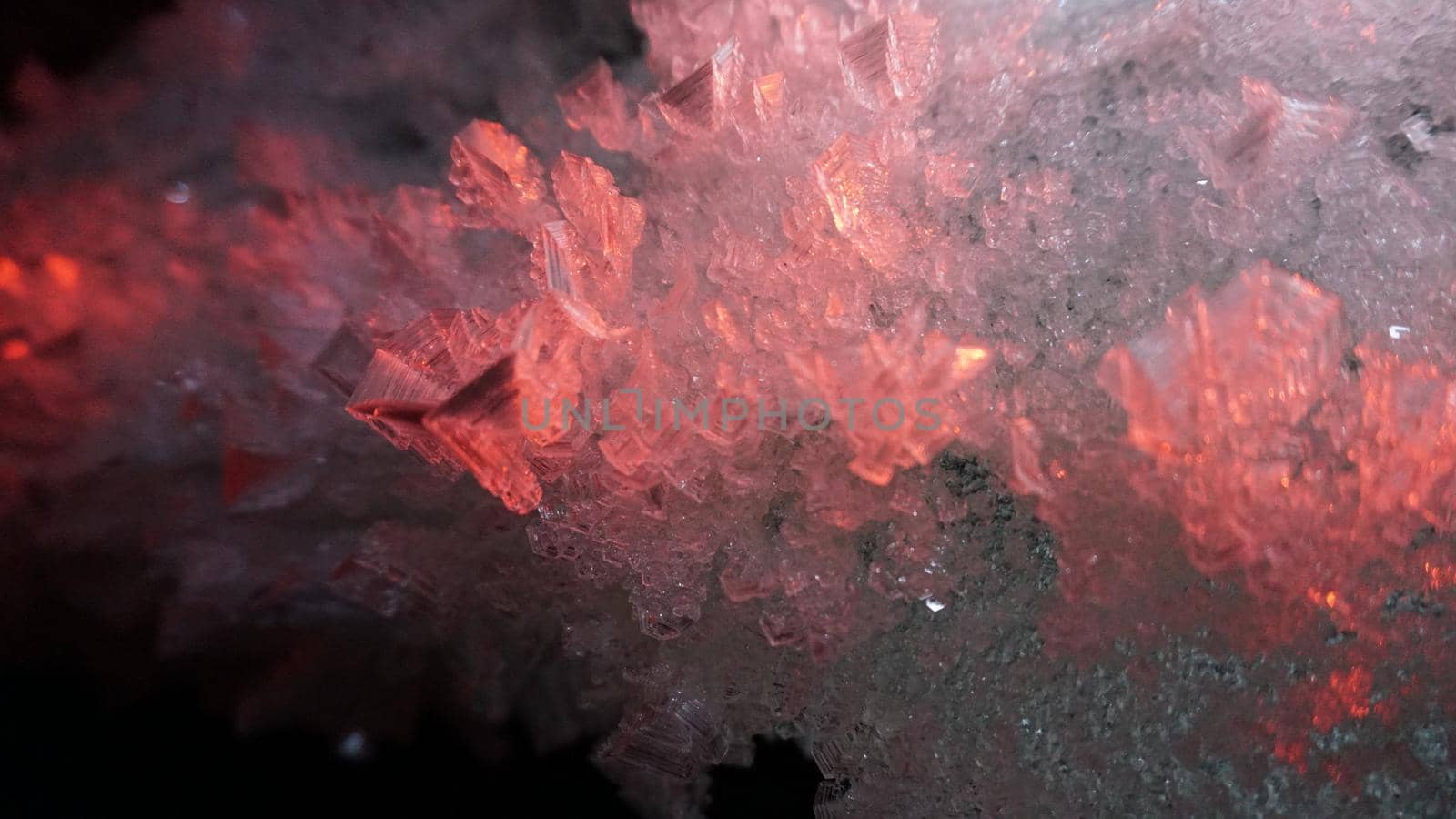 Macro photography of ice growths in a cave. Snow and ice of interesting shapes grow on the walls of the cave. Stalactites hang. Huge ice walls shimmer from the light of the lantern. Almaty, Kazakhstan