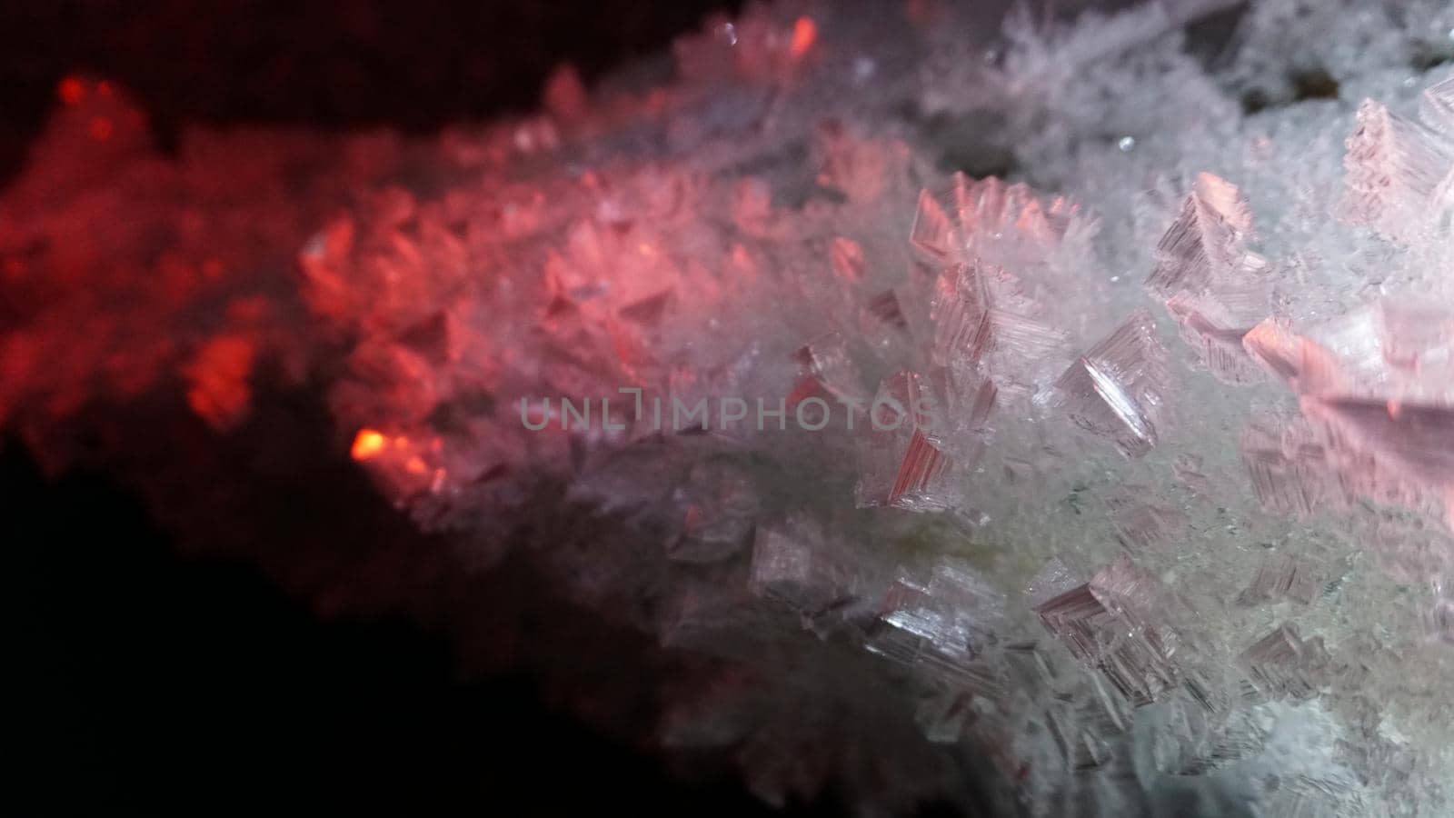 Macro photography of ice growths in a cave. Snow and ice of interesting shapes grow on the walls of the cave. Stalactites hang. Huge ice walls shimmer from the light of the lantern. Almaty, Kazakhstan