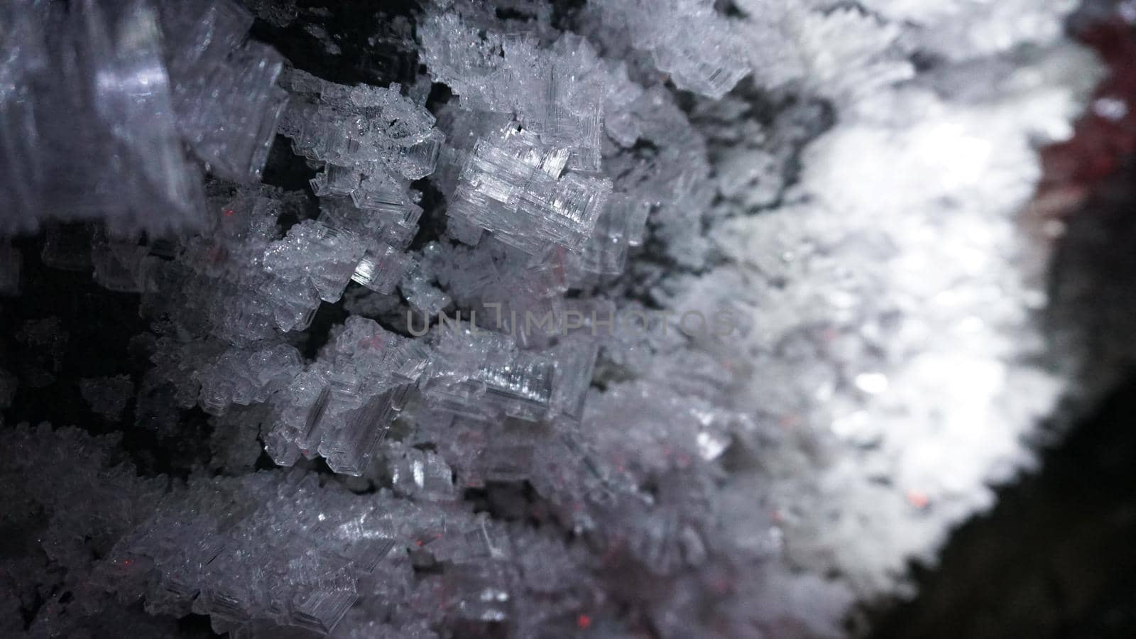 Macro photography of ice growths in a cave. Snow and ice of interesting shapes grow on the walls of the cave. Stalactites hang. Huge ice walls shimmer from the light of the lantern. Almaty, Kazakhstan