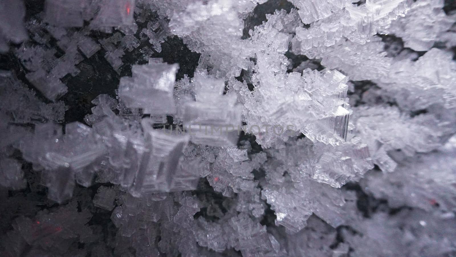 Macro photography of ice growths in a cave. Snow and ice of interesting shapes grow on the walls of the cave. Stalactites hang. Huge ice walls shimmer from the light of the lantern. Almaty, Kazakhstan