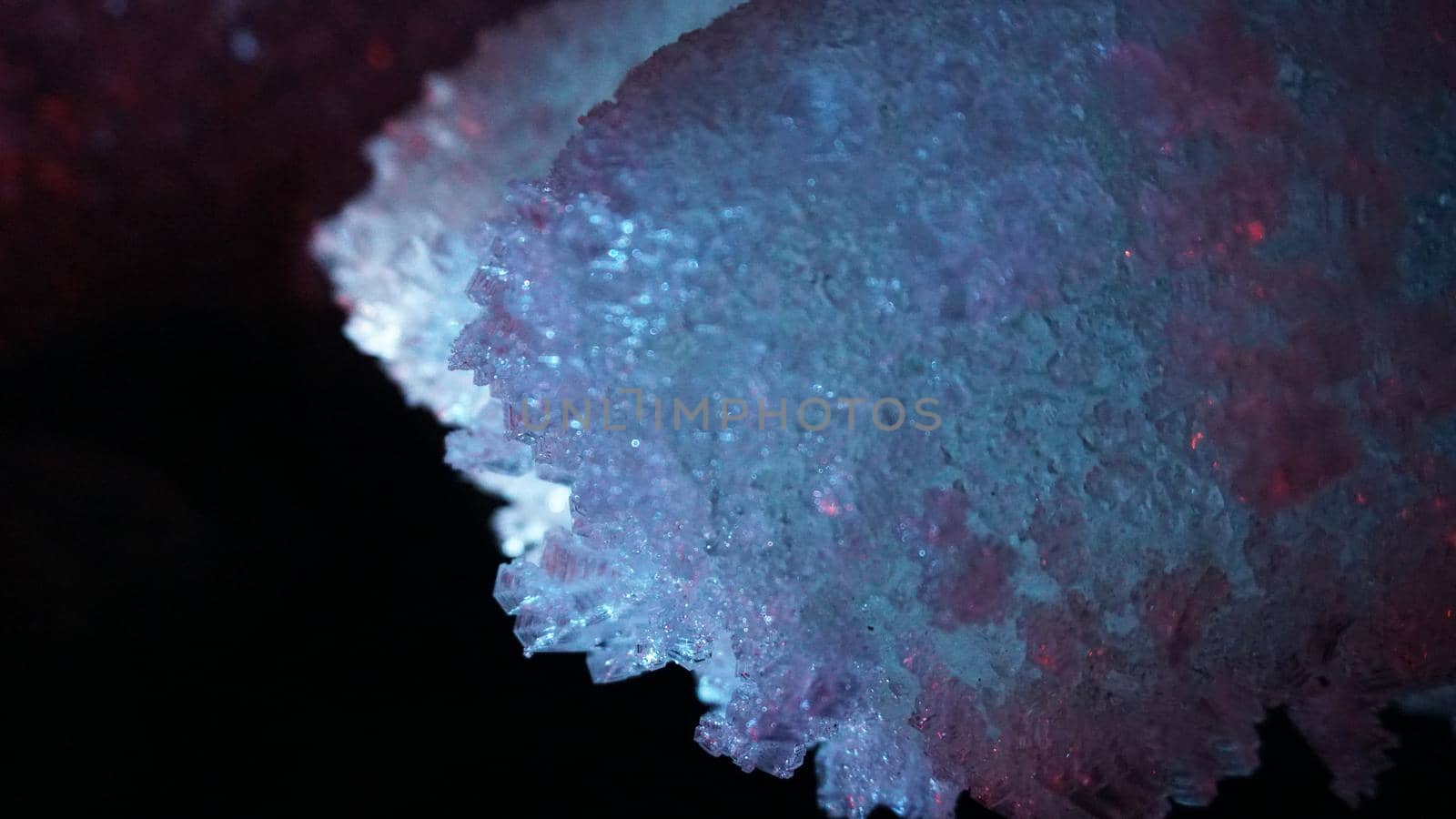 Macro photography of ice growths in a cave. Snow and ice of interesting shapes grow on the walls of the cave. Stalactites hang. Huge ice walls shimmer from the light of the lantern. Almaty, Kazakhstan