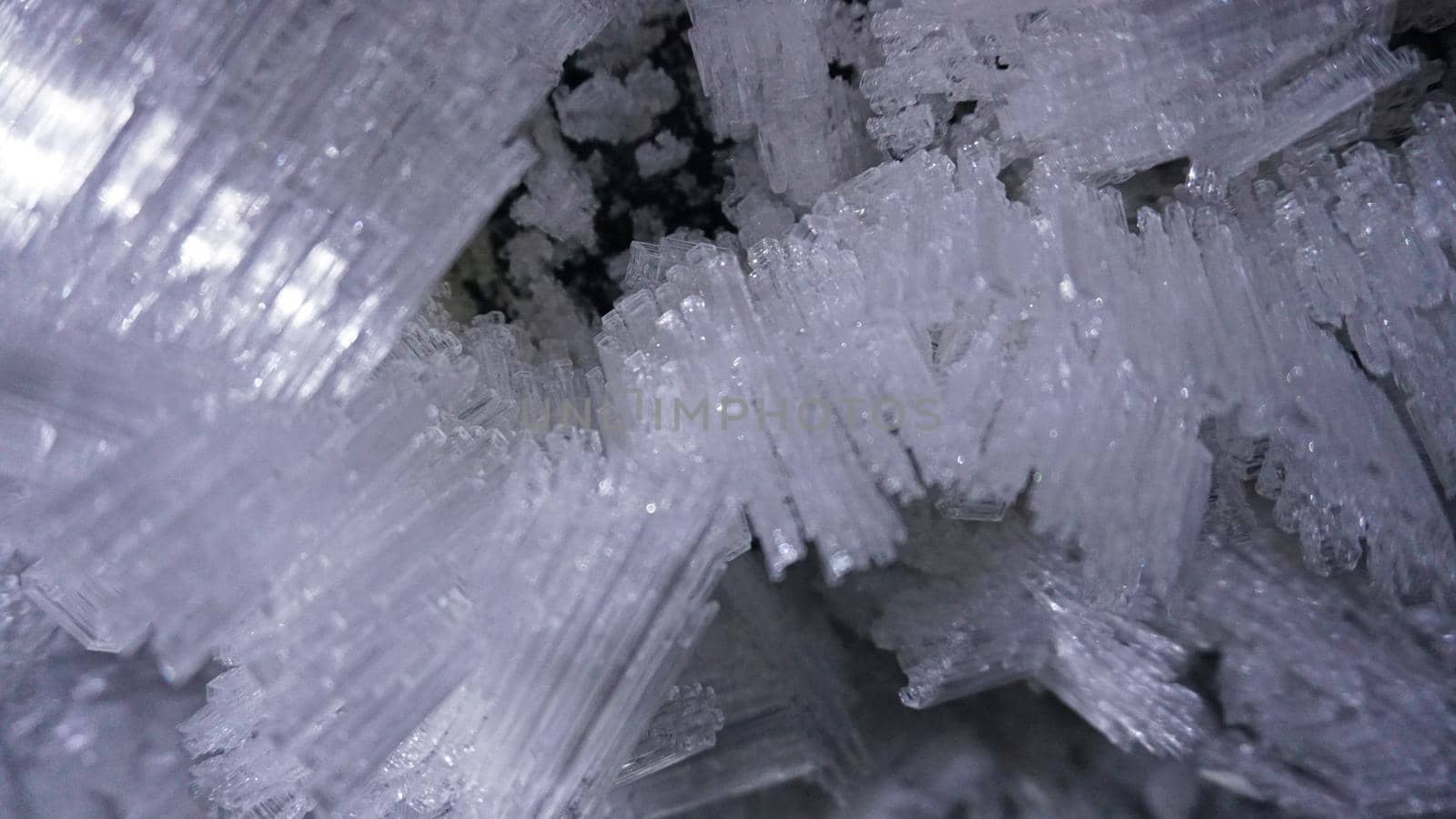 Macro photography of ice growths in a cave. Snow and ice of interesting shapes grow on the walls of the cave. Stalactites hang. Huge ice walls shimmer from the light of the lantern. Almaty, Kazakhstan