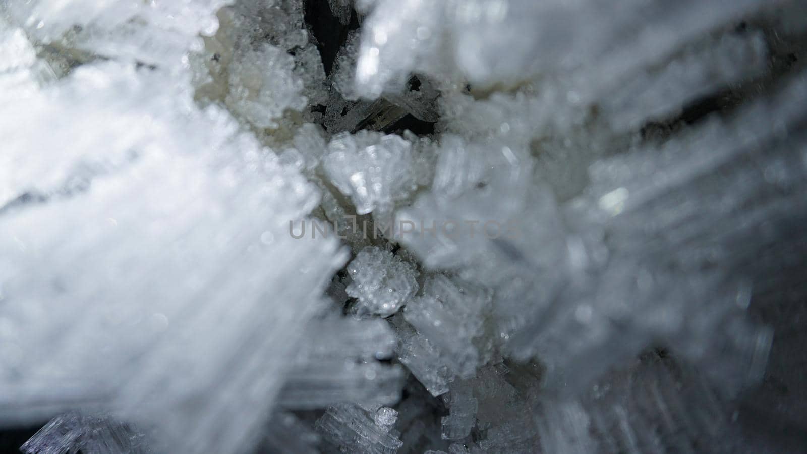 Macro photography of ice growths in a cave. Snow and ice of interesting shapes grow on the walls of the cave. Stalactites hang. Huge ice walls shimmer from the light of the lantern. Almaty, Kazakhstan