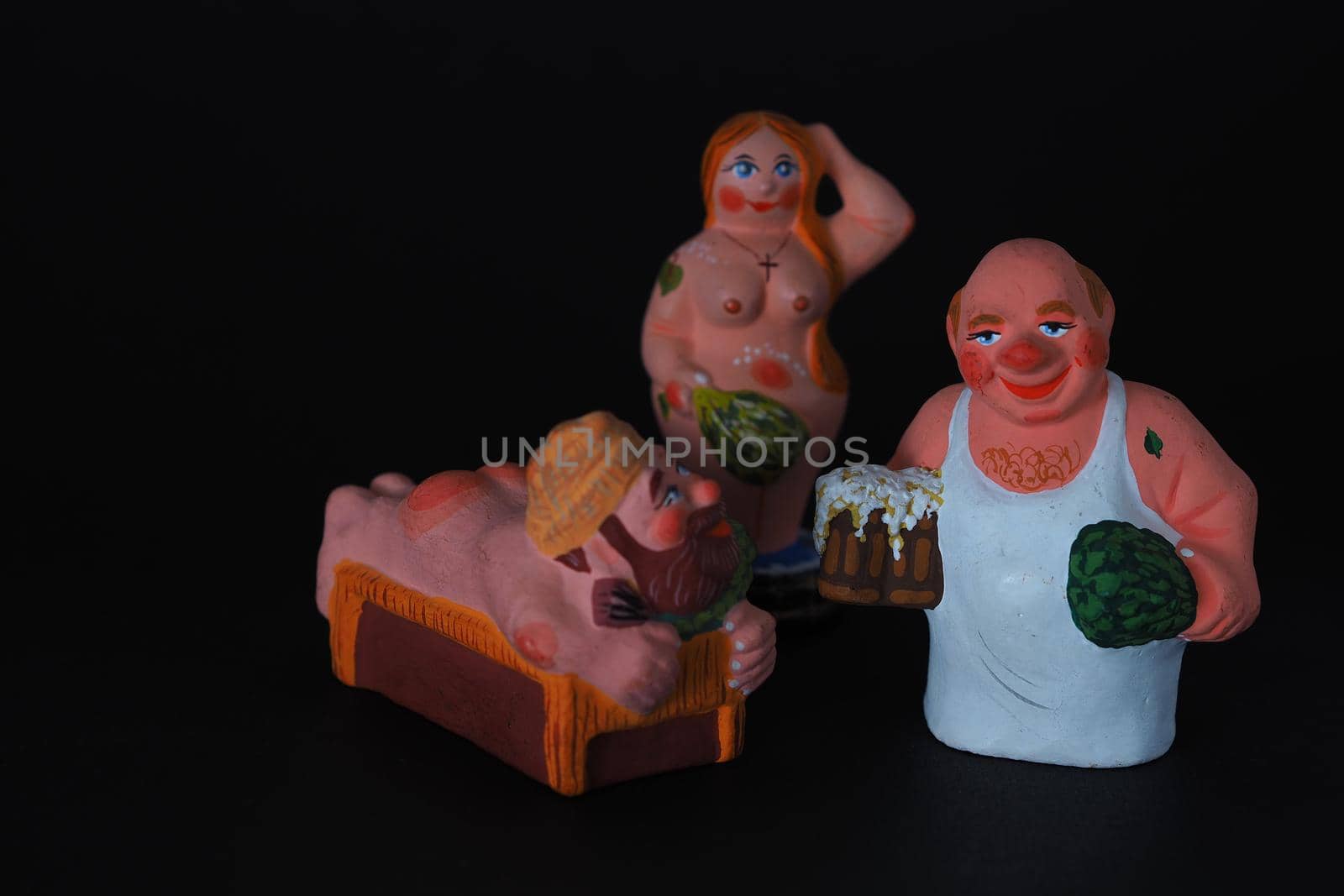 Funny figurines of plaster, clay and ceramics. Bath. The people in the steam room. It's a macro- Black background.