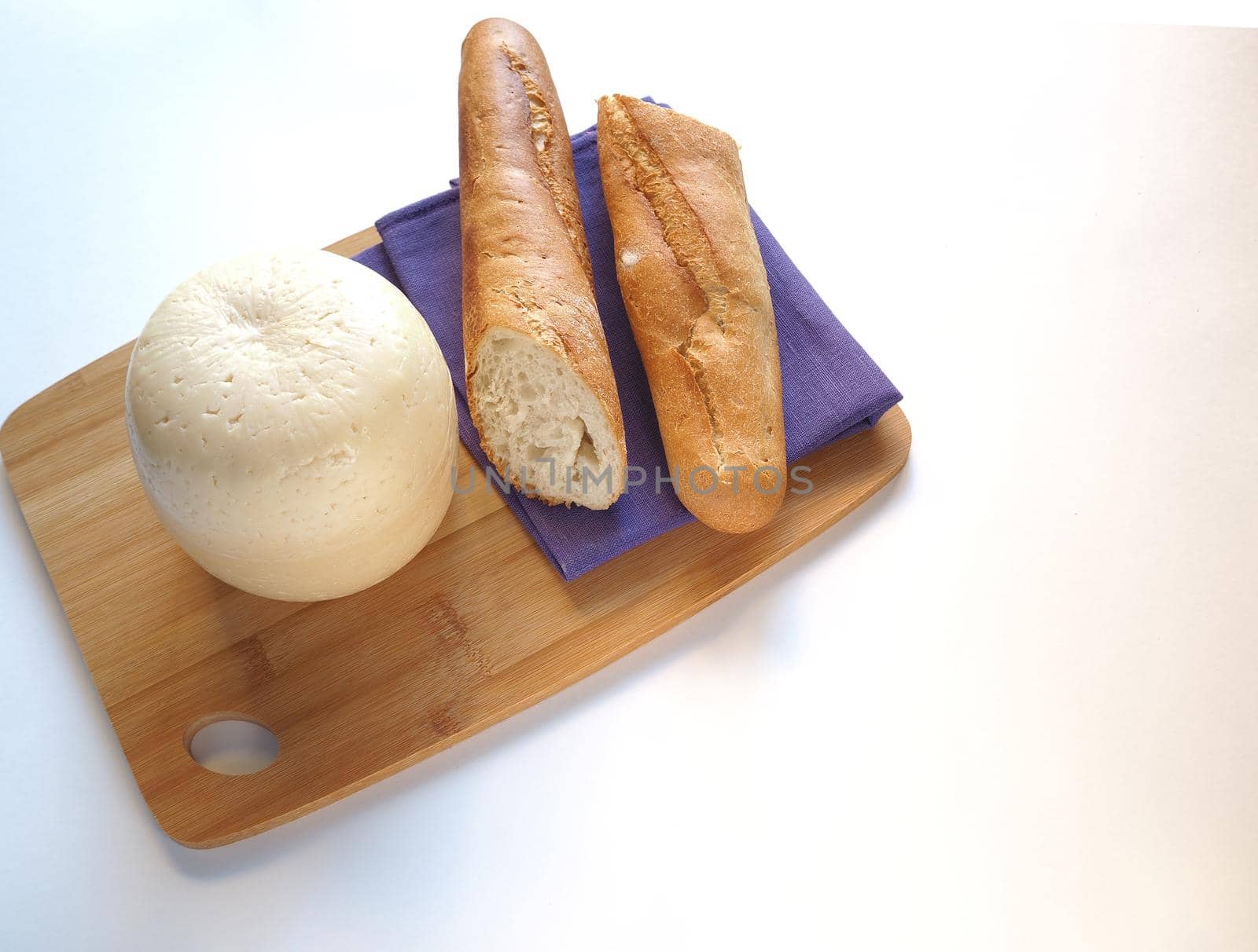 Cheese with baguette on a wooden board. Close-up. White background.