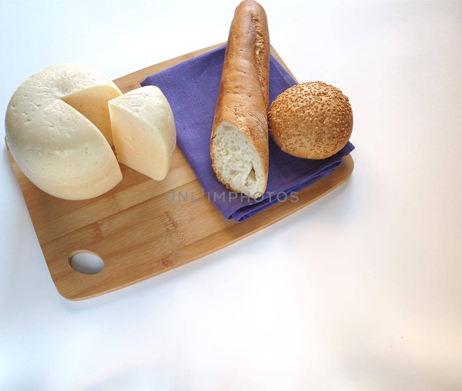 A large piece of cheese on a wooden tray with fresh bread. by Olga26