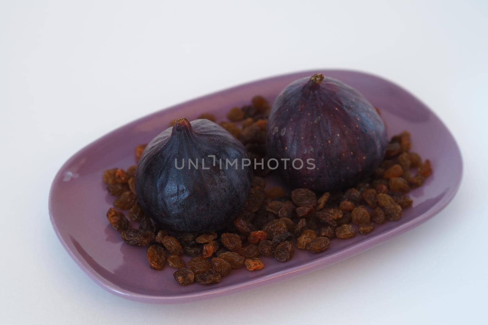 Fruit. Fig and raisins on a purple platter. White background. Close-up. High quality photo