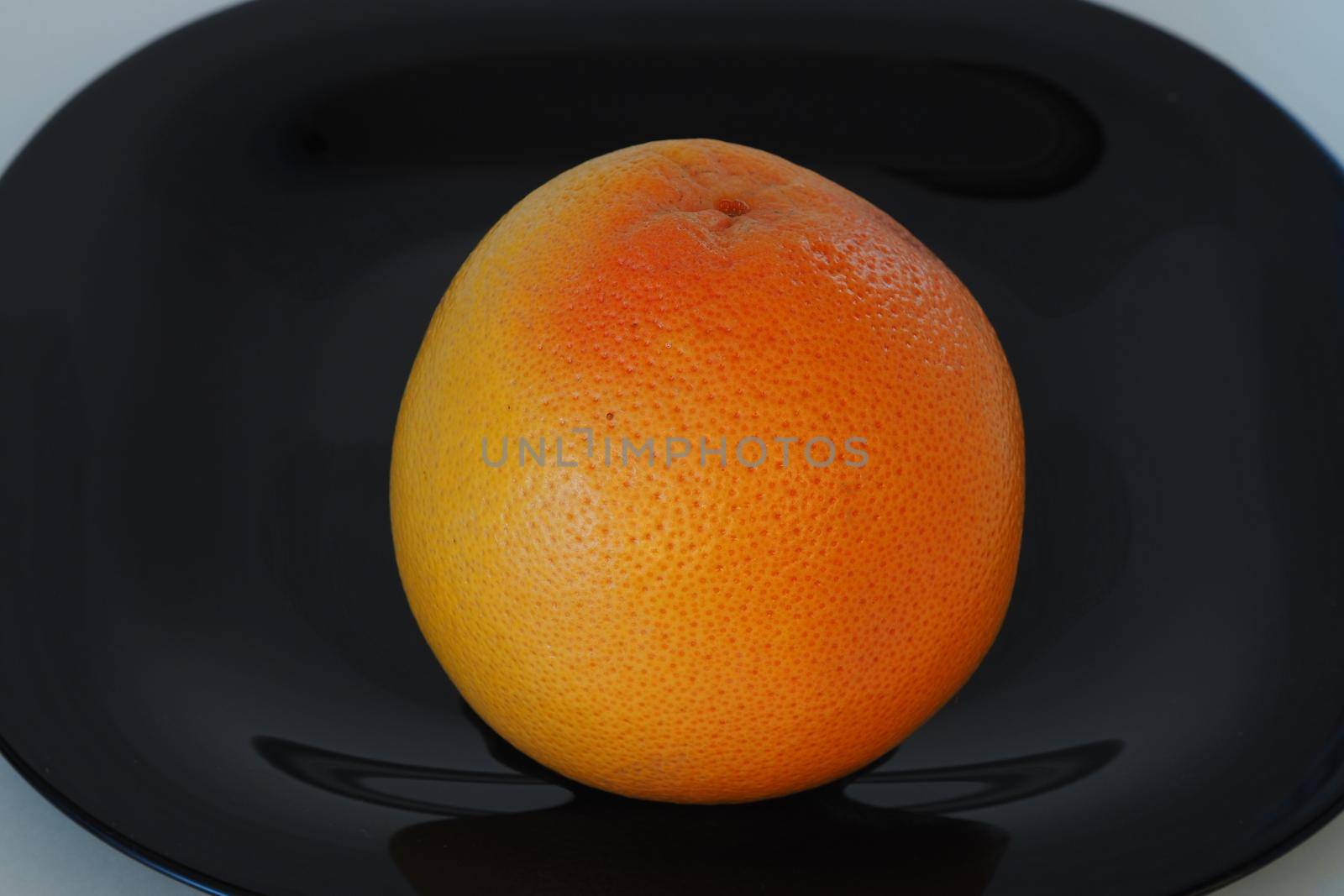 Fruits are citrus fruits. Orange grey fruit on a black plate. by Olga26