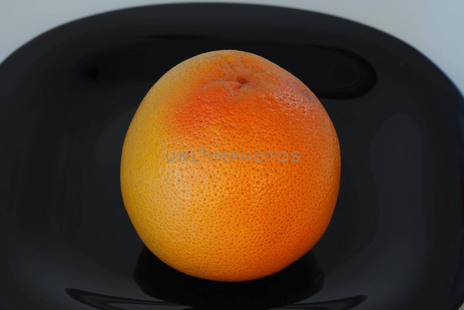 Fruits are citrus fruits. Orange grey fruit on a black plate. by Olga26