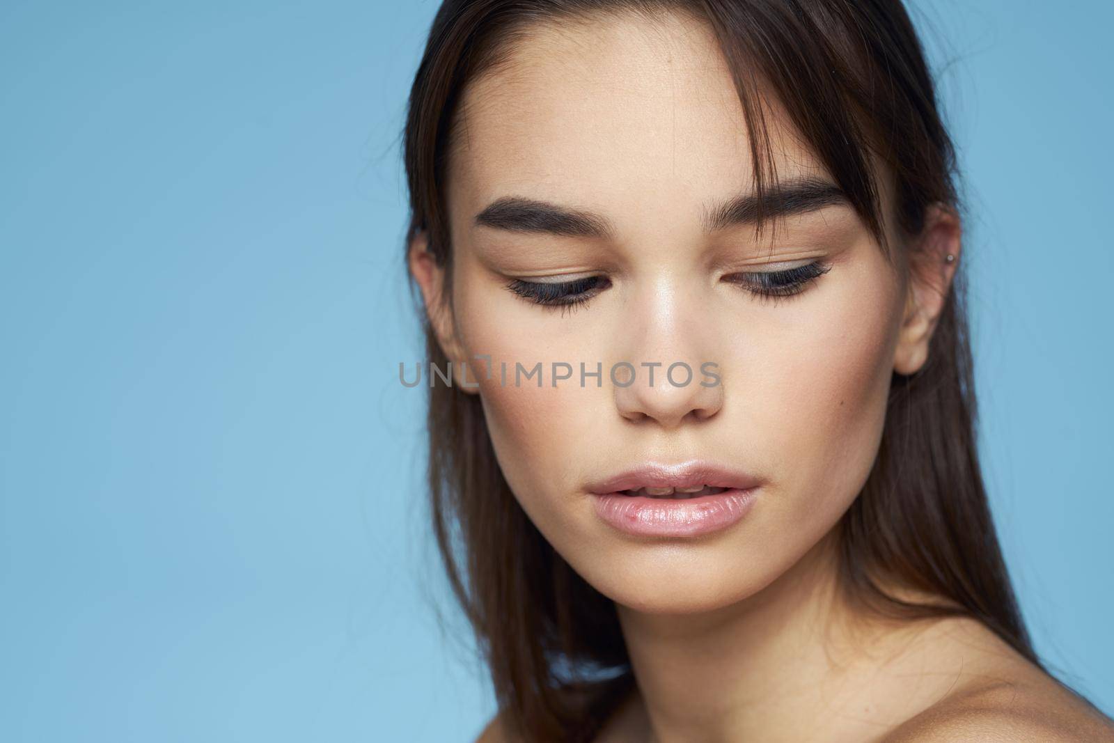 Woman with naked shoulders long hair cosmetics attractive look blue background. High quality photo