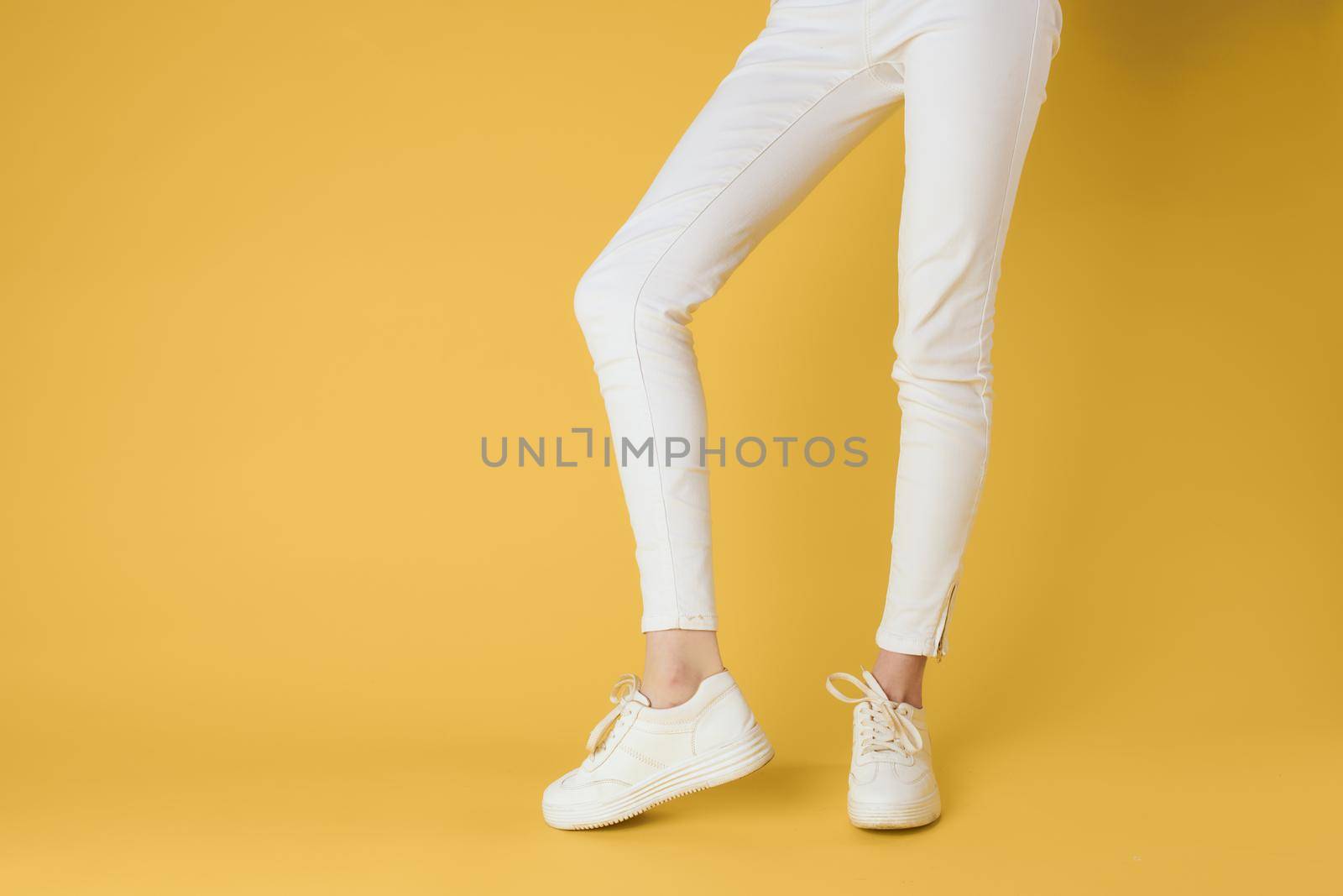 Womens legs white pants sneakers fashion clothes luxury street style yellow background by SHOTPRIME