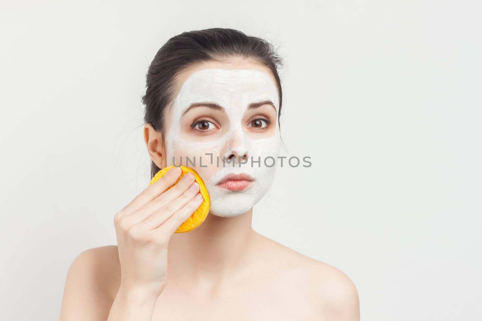 cute brunette with sponges in hands cream mask scrub rejuvenation. High quality photo