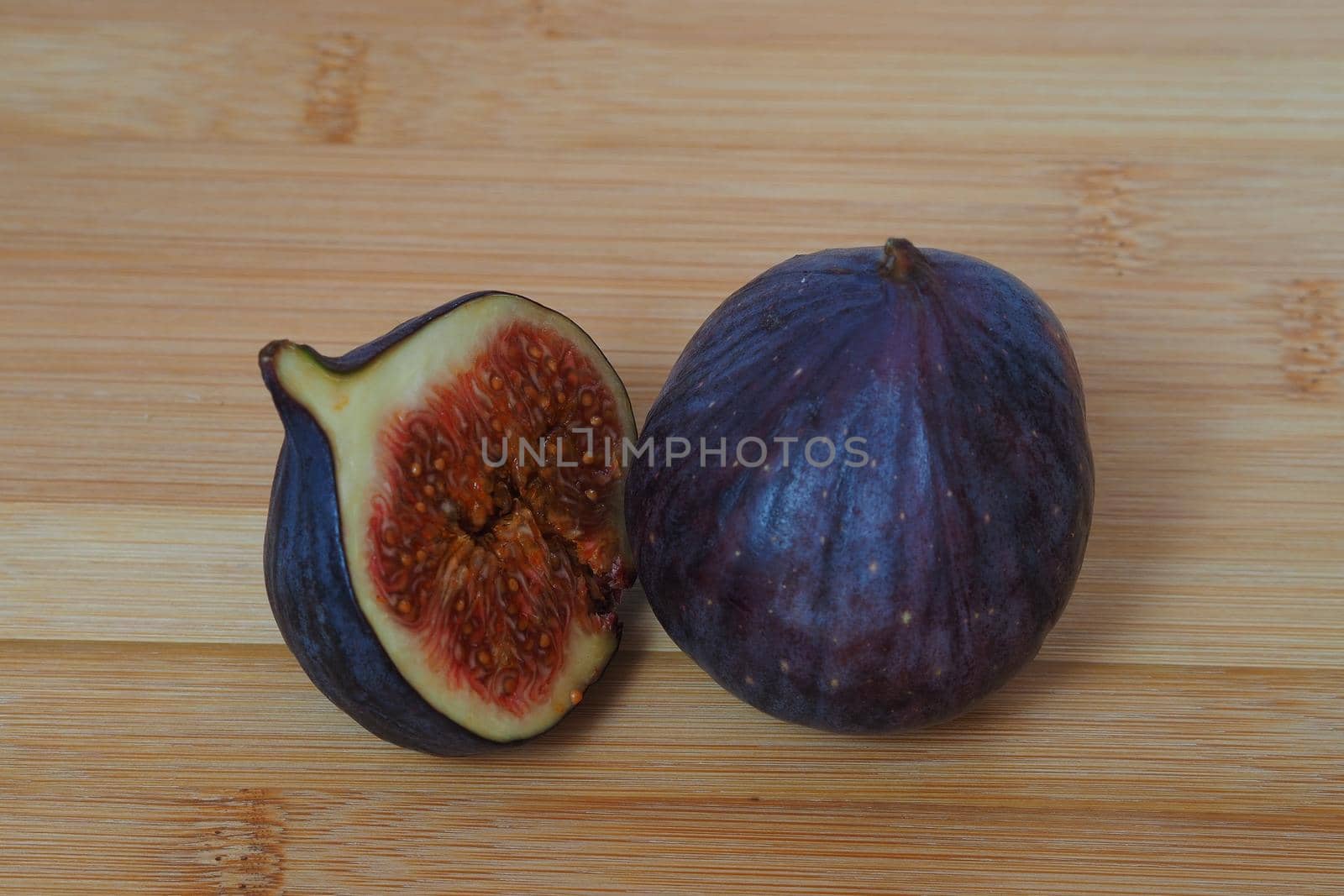 Fruit. The fig is whole and slice, close-up, wooden background. by Olga26