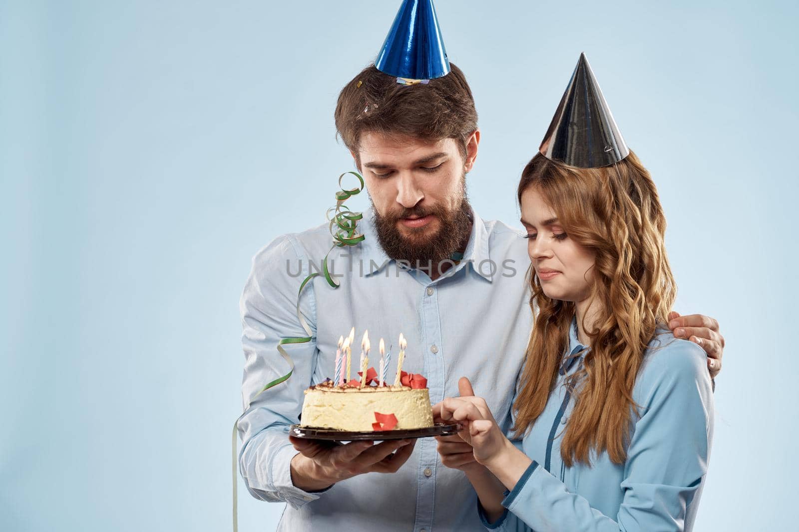 Birthday man woman in party hats on a blue background and cake with candles. High quality photo