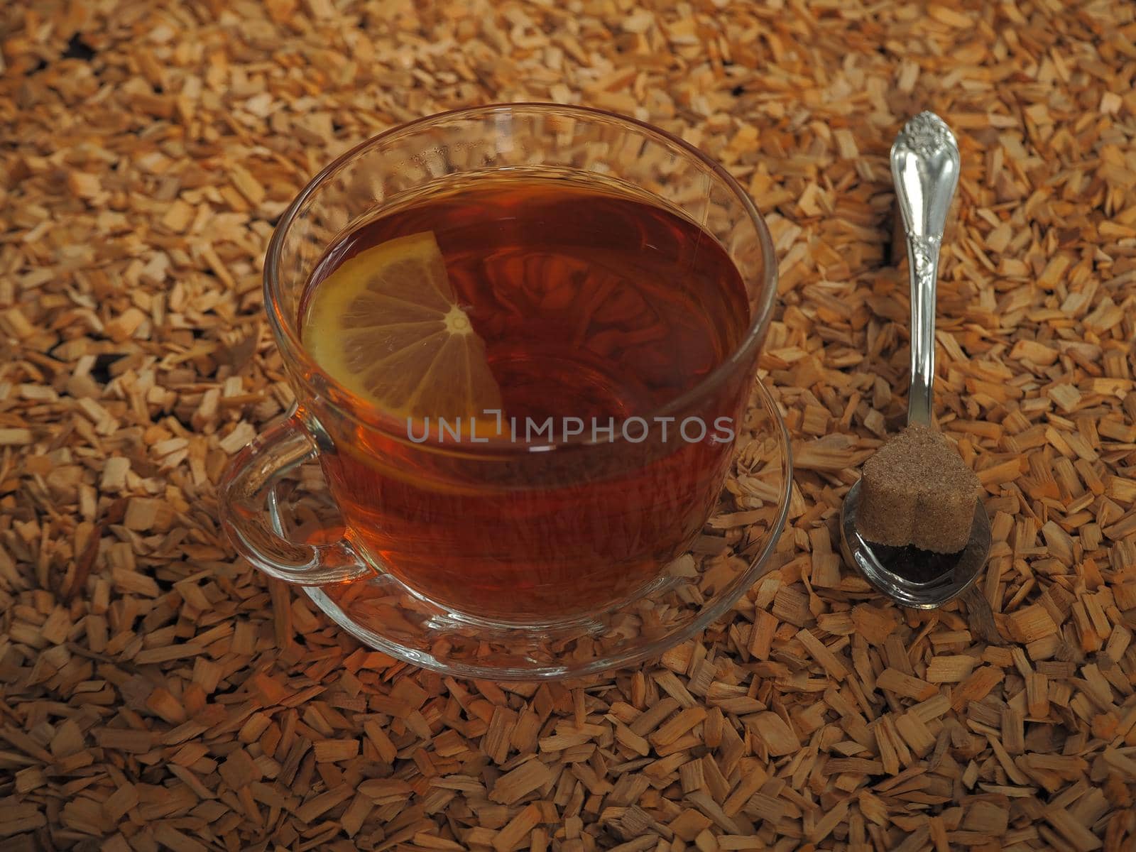 Black tea with lemon in a transparent cup on a wooden tray.