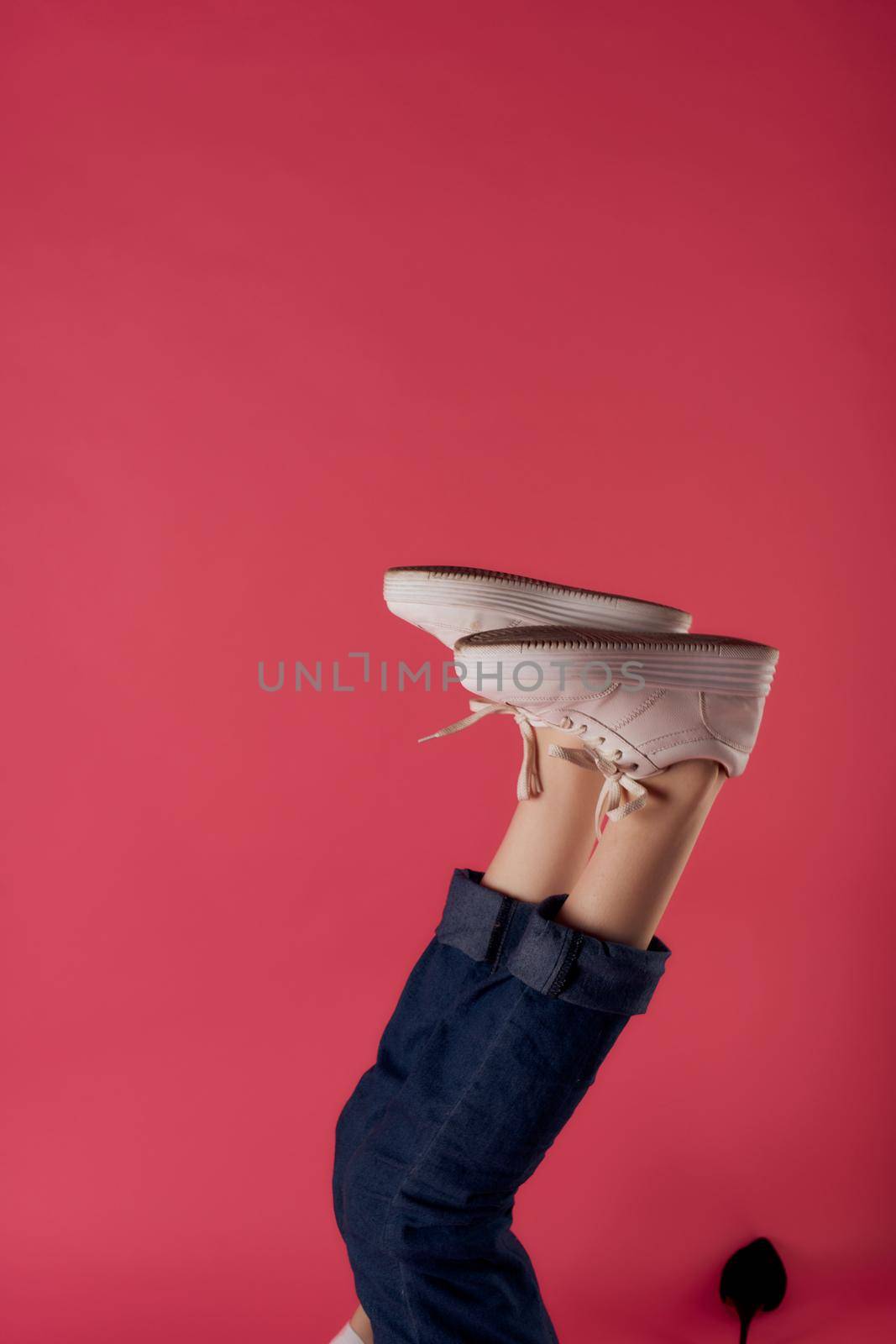 inverted female legs in white sneakers fashion studio pink background by SHOTPRIME