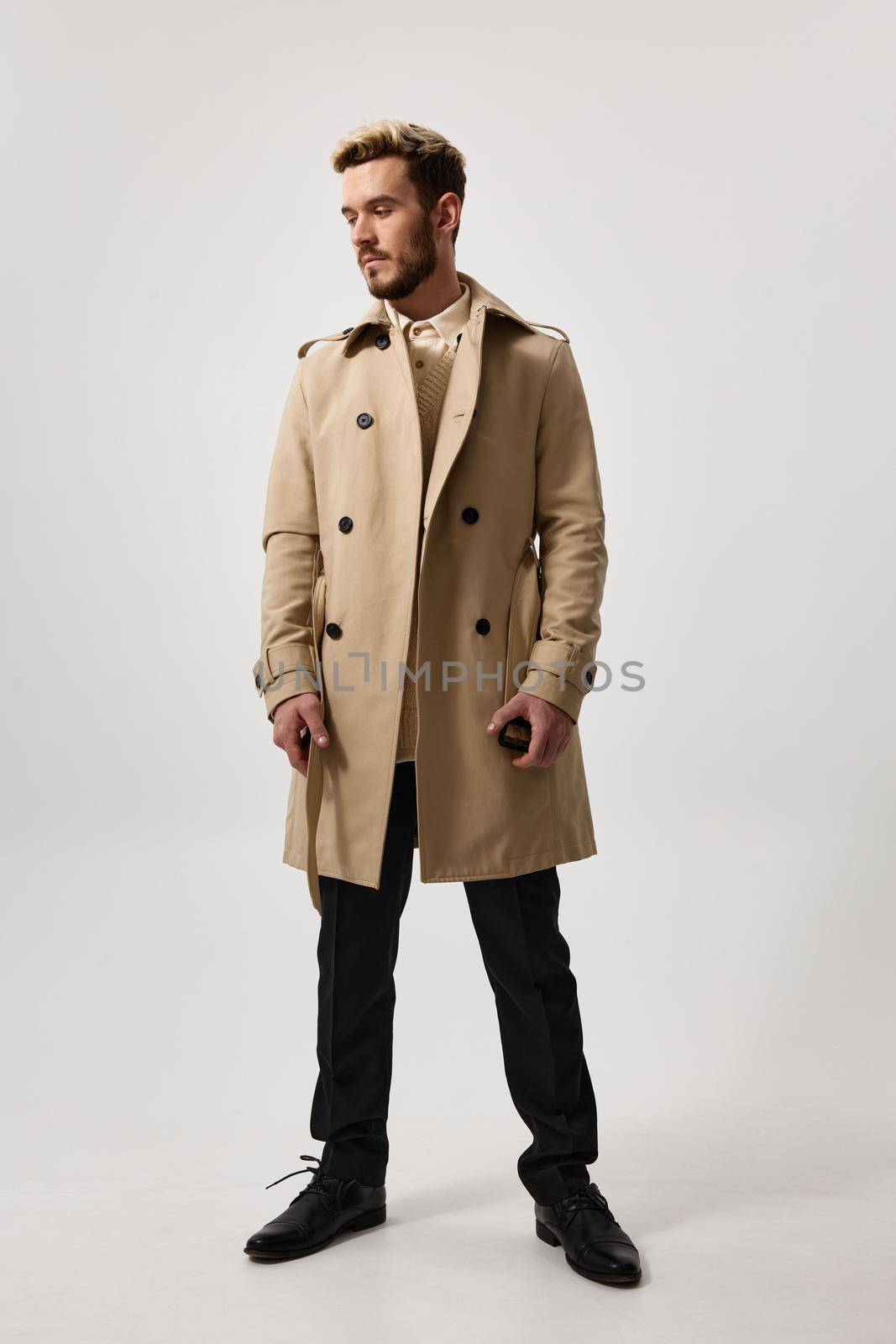 gentlemen in a beige coat and full-length trousers on a light background hairstyle model glasses. High quality photo