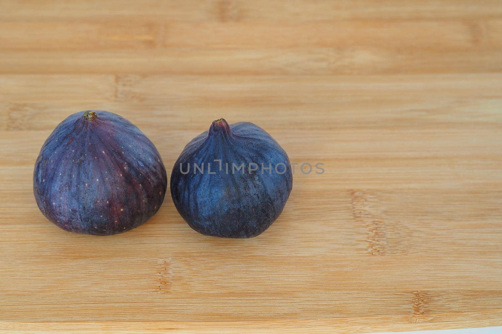 The fig is purple on a wooden background. by Olga26