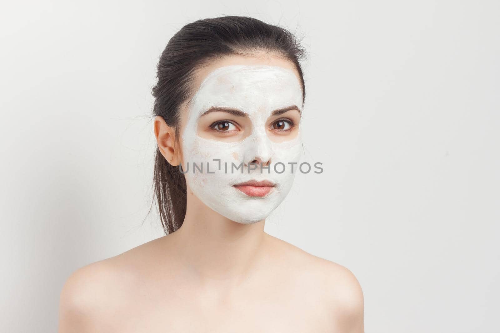 pretty brunette with cream face mask bare shoulders smile cropped view. High quality photo