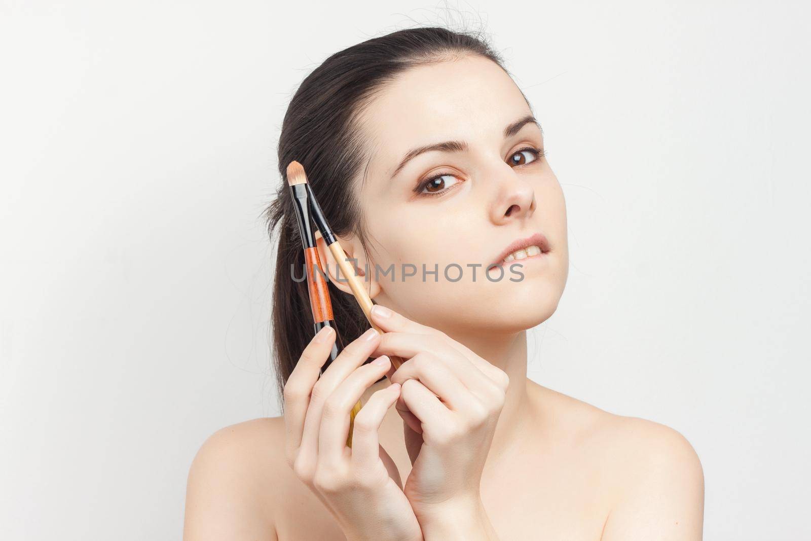 pretty brunette with a brush in her hands applying makeup skincare procedures. High quality photo