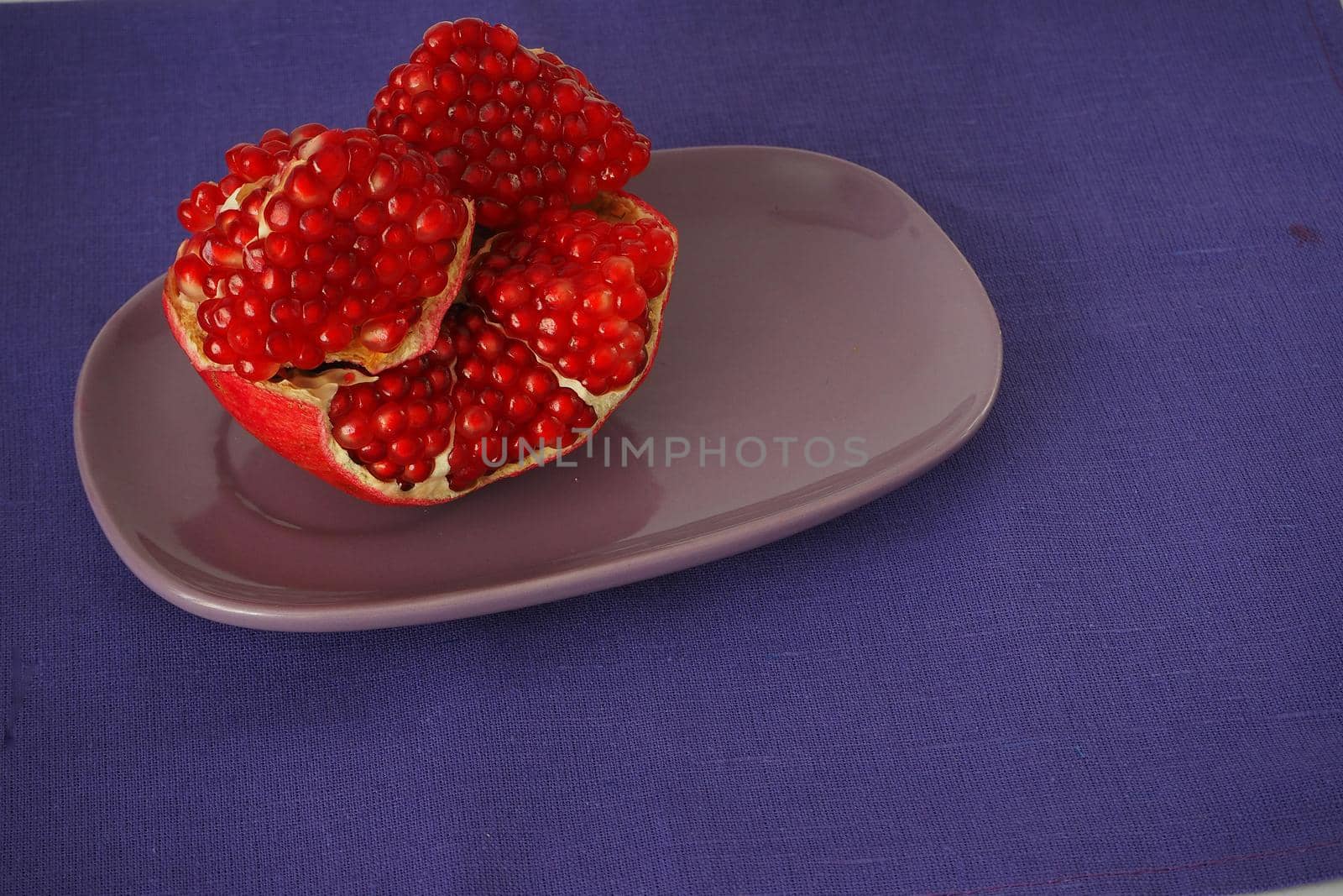 The fruit of a ripe pomegranate, red fruit with juicy grains. Isolated on a blue background.