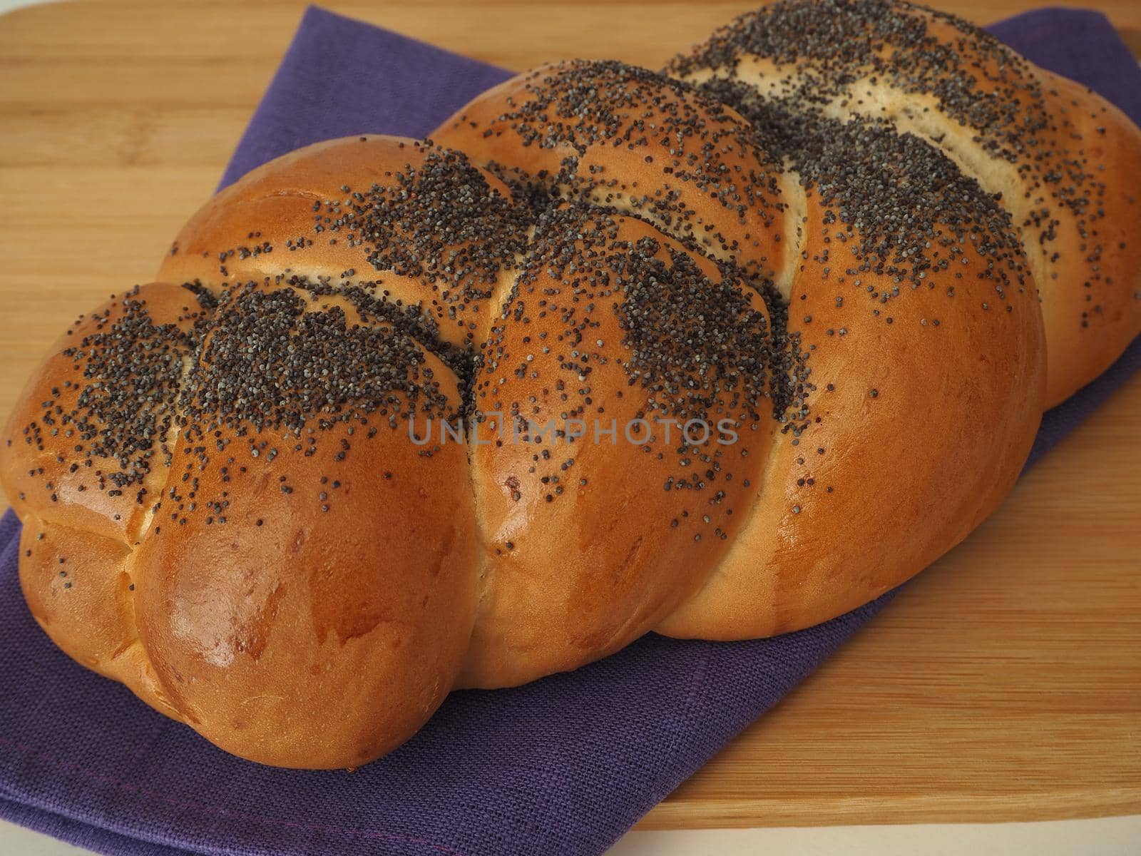 bread pigtail with poppy close-up on a wooden Board. by Olga26