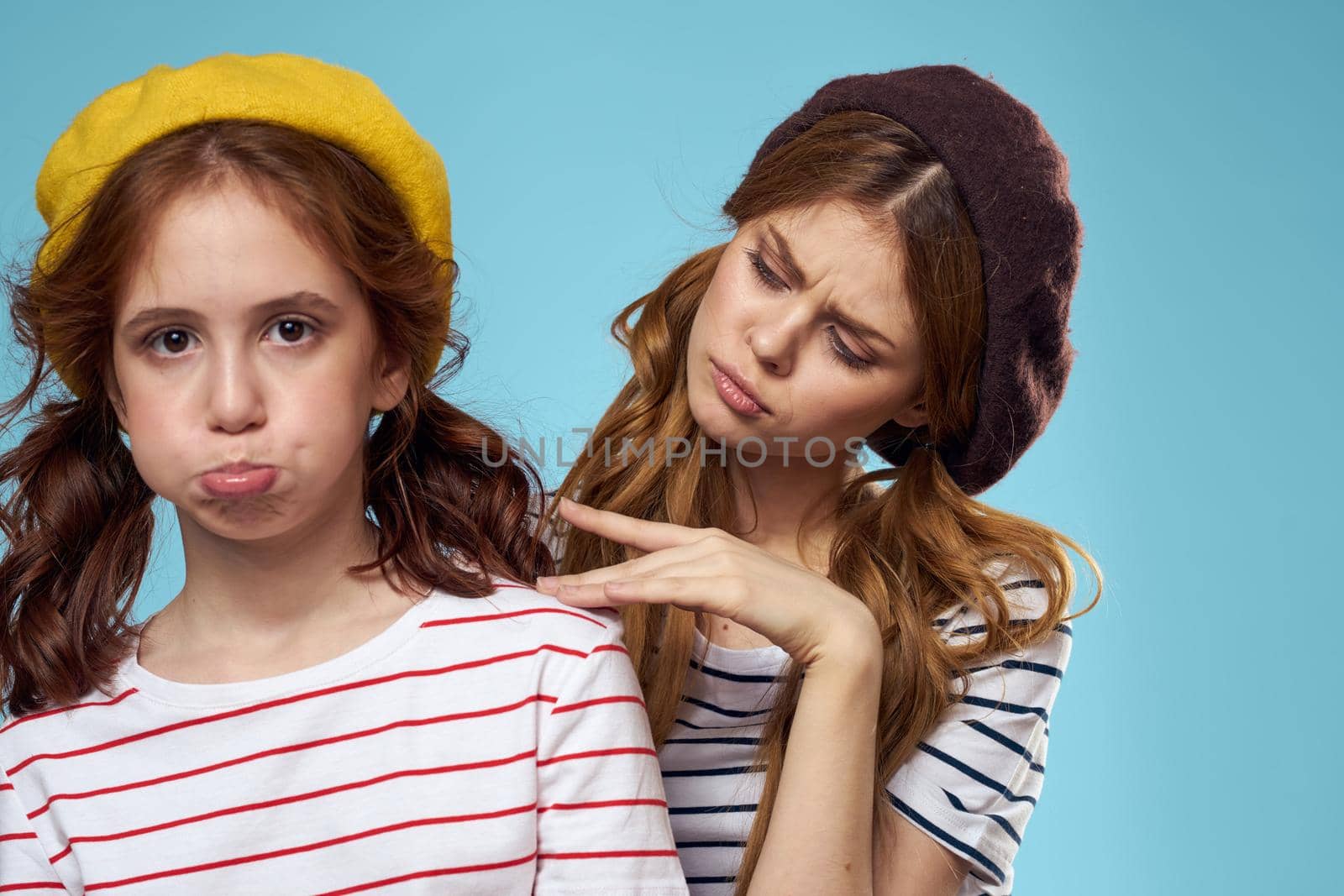 Mom and daughter striped T-shirts hugs fun lifestyle blue background. High quality photo