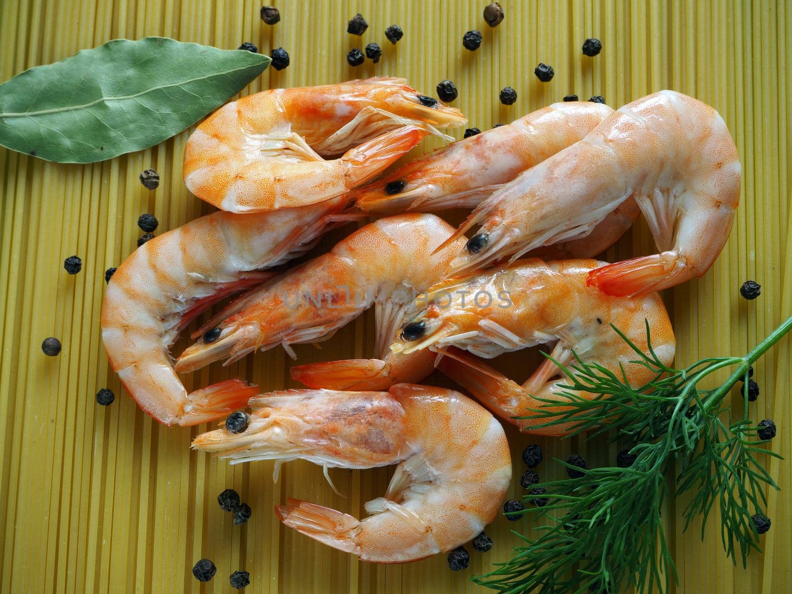 Large prawns with spices and spaghetti. Prawns with dill and pepper close-up. Bright background.