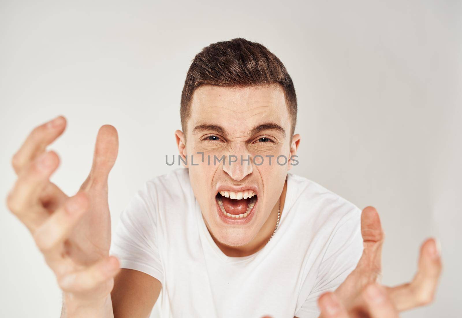 Crazy man gesturing with his hands on a light background Scream stress irritability. High quality photo