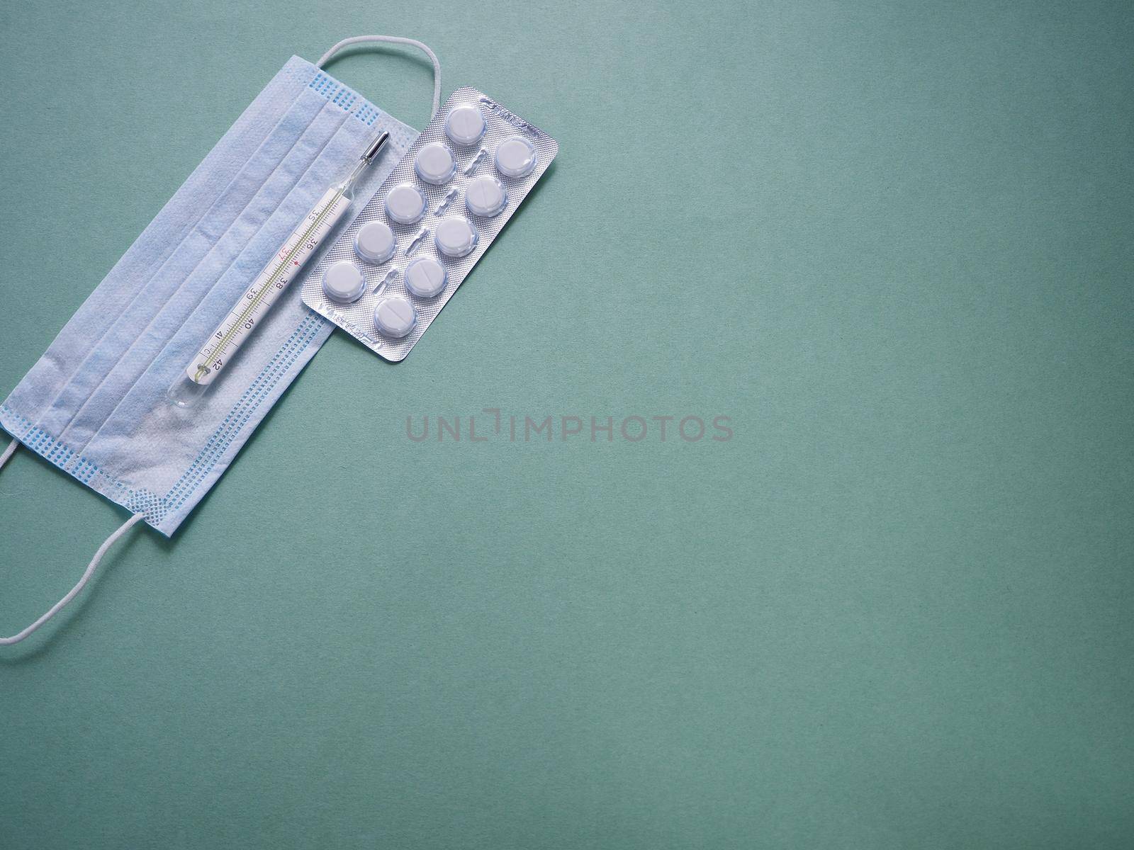 Tablets in blister packaging, body thermometer and personal protective equipment. close-up.