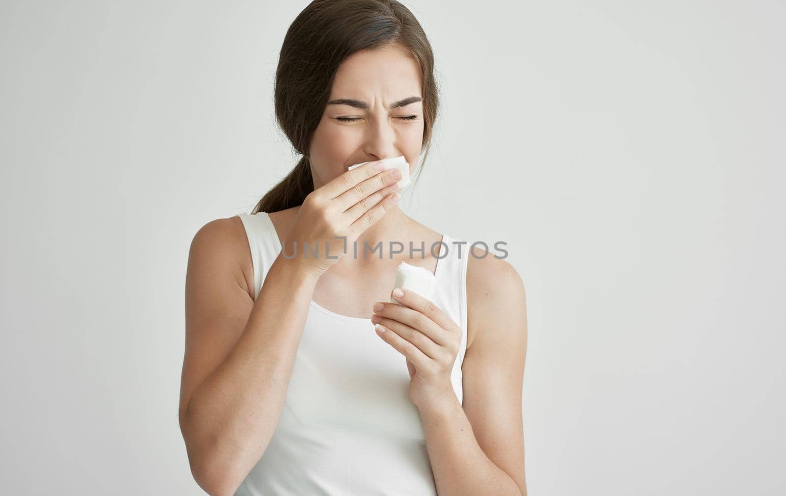 brunette in white t-shirt wipes her face with a handkerchief health problems cold. High quality photo