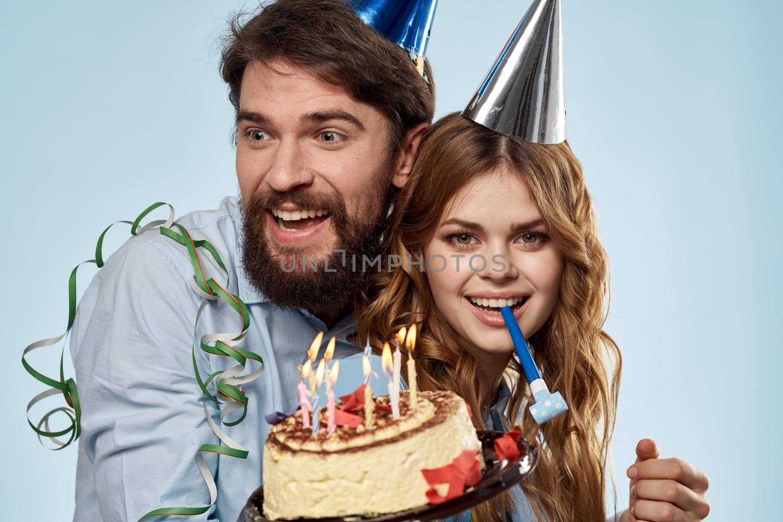 Birthday man woman in party hats on a blue background and cake with candles. High quality photo