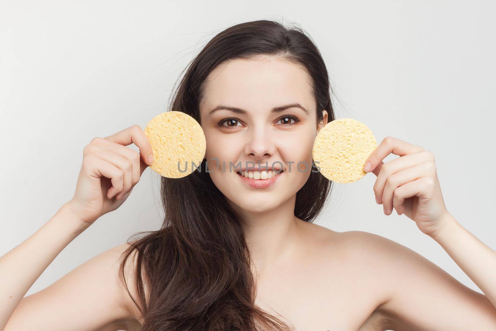 woman with bare shoulders loose hair clean skin sponges in hands. High quality photo
