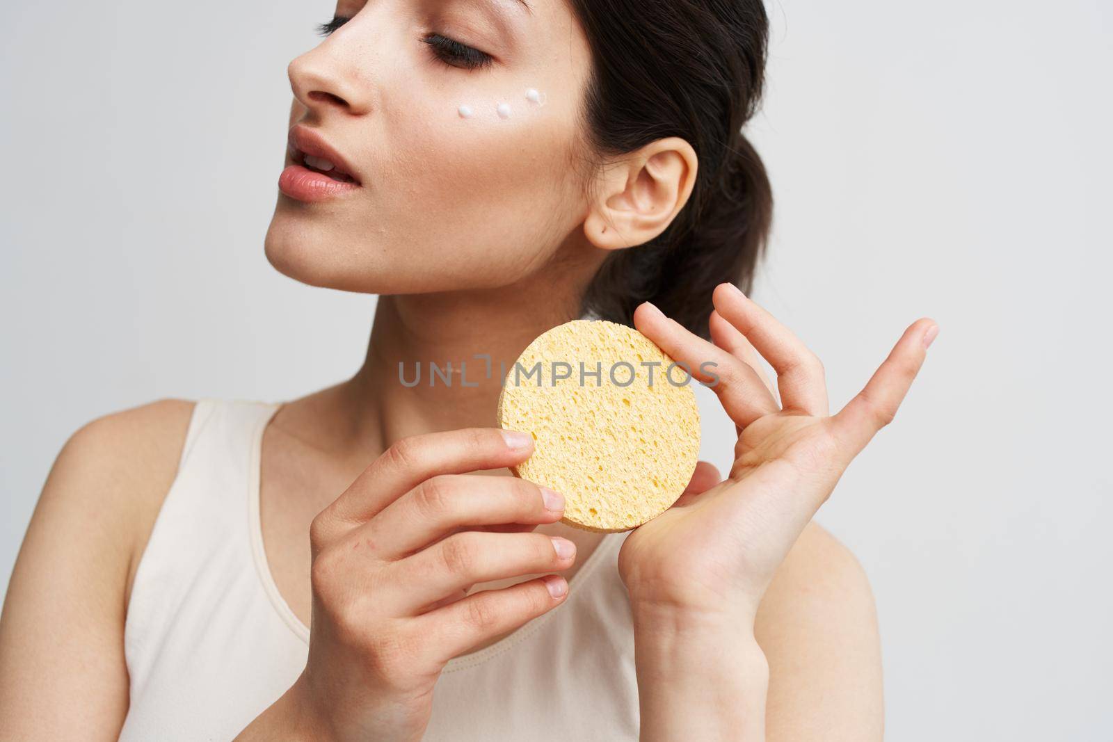 Beautiful brunette holding a sponge in her hands clean health skin close-up. High quality photo