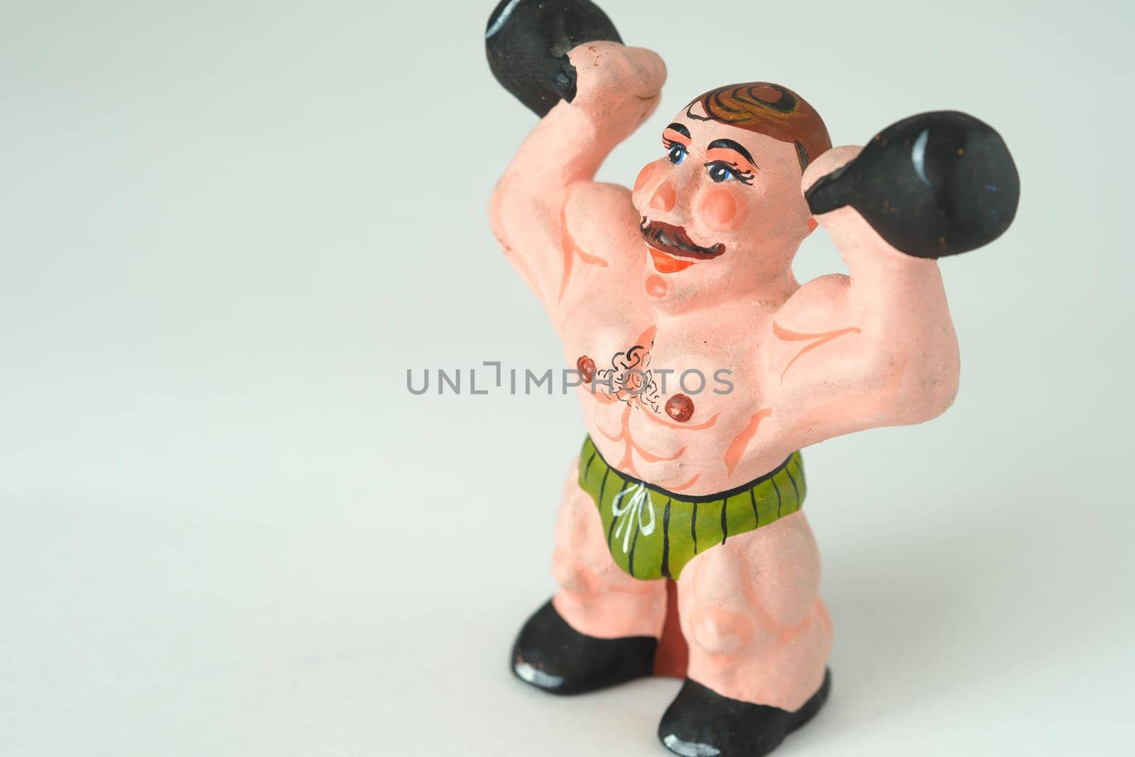 Athlete. The man with the weights. Decorative figurines made of ceramics, plaster and clay. Close-up.