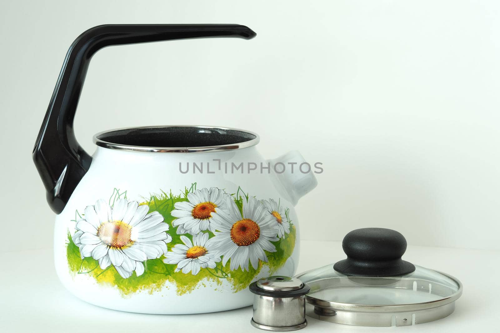 The kettle is white enamelled with a whistle and a pattern. High quality photo