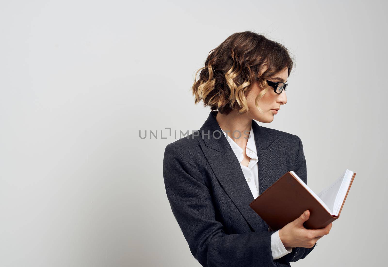 Business woman in a classic suit with a book in her hands on a light background indoors. High quality photo