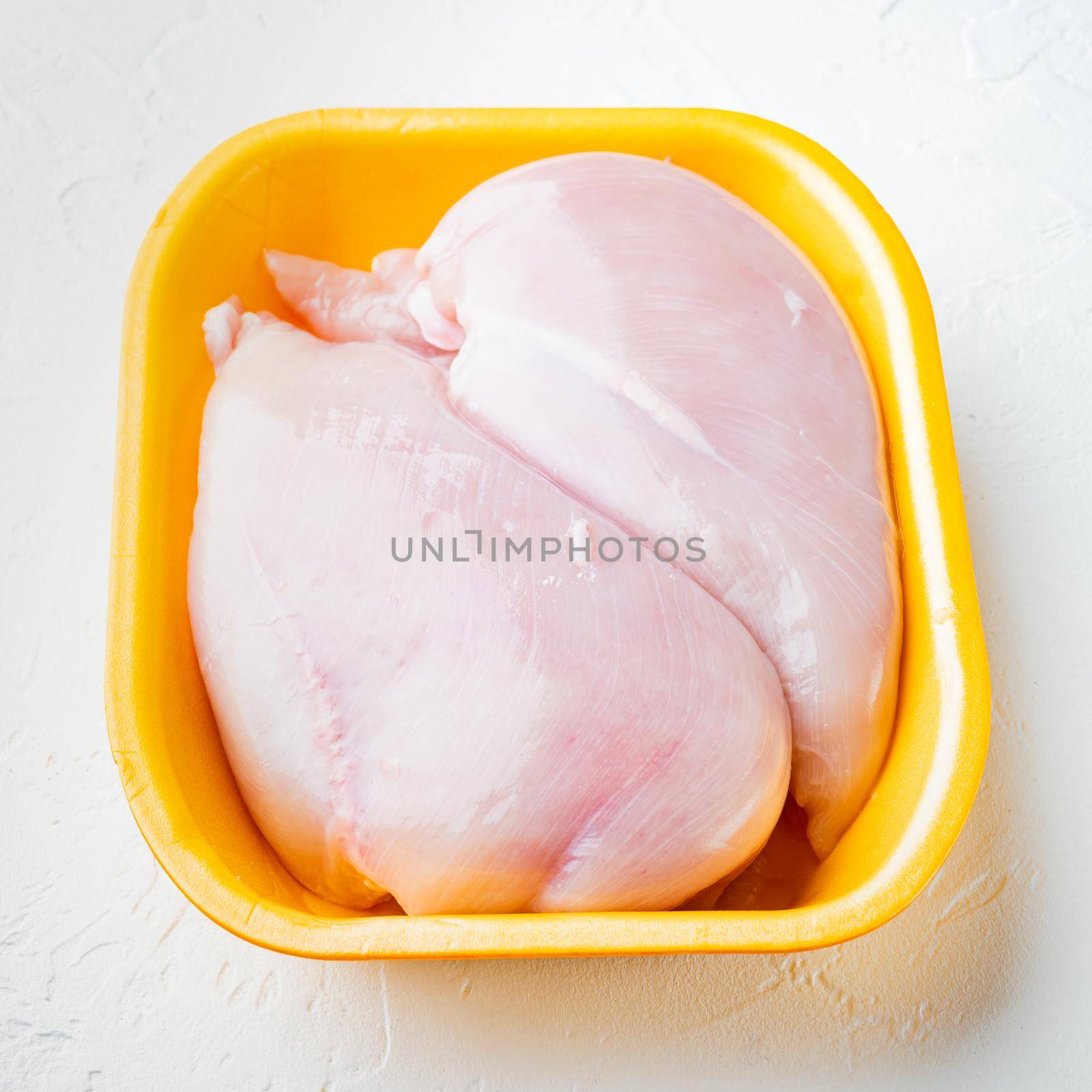 Raw chicken breast fillets in tray, on white background
