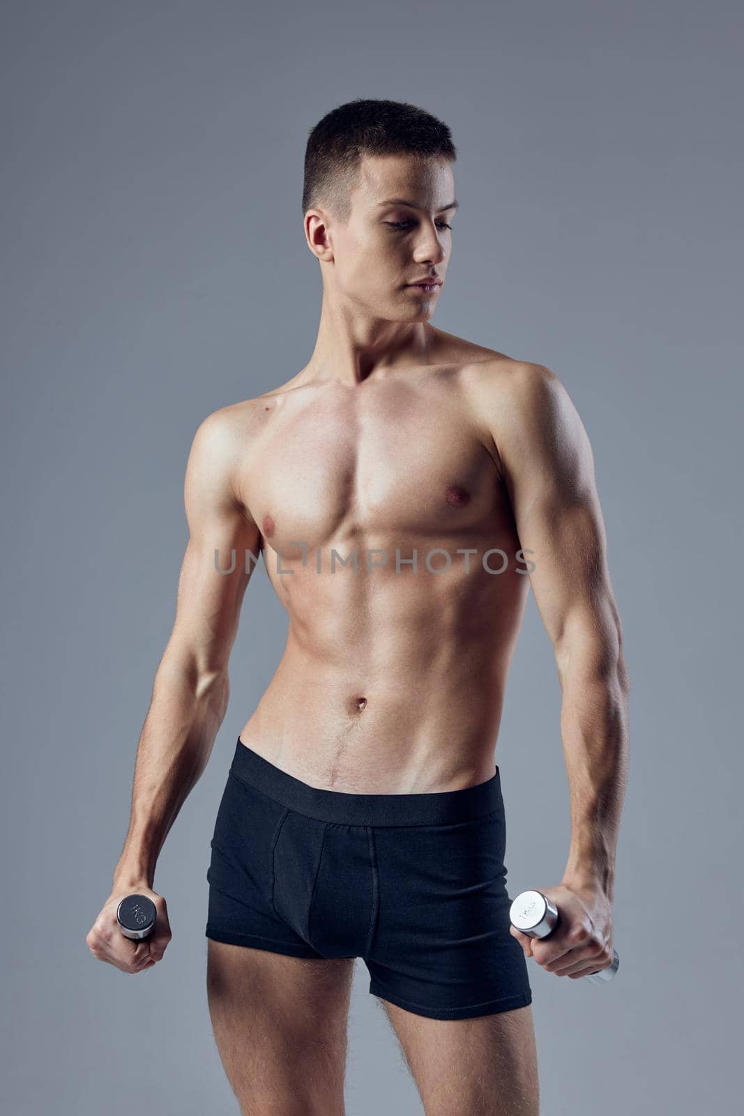 sporty man in black shorts with dumbbells in hands pumped up body posing exercise. High quality photo