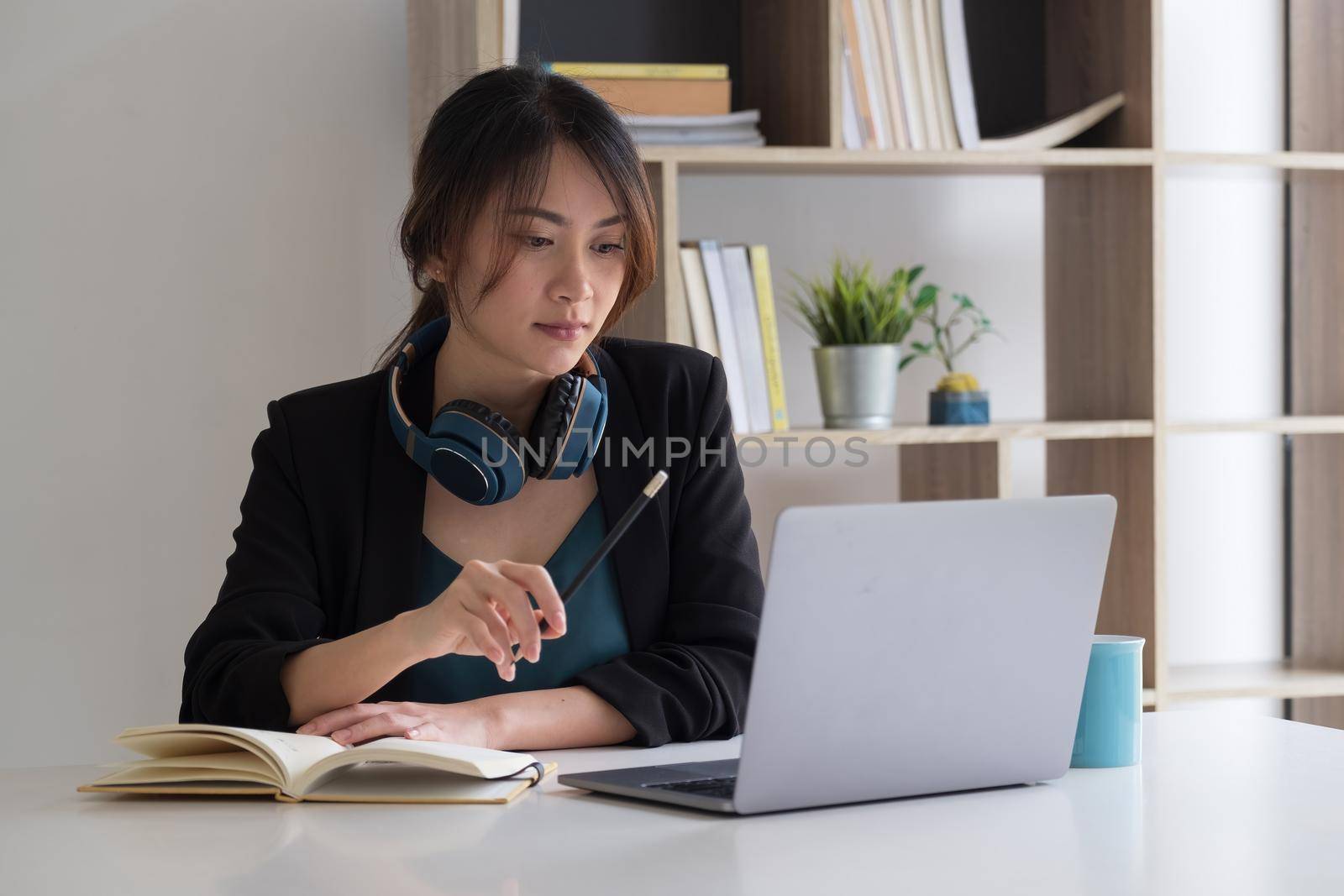 Young asian woman student e learning watching video training course sit at home office desk. girl look at laptop computer study with online teacher making notes