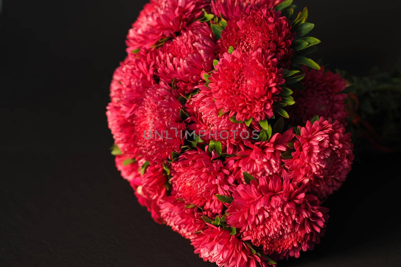 Bouquet of flowers. Asters are pink. Close-up, on a black background.