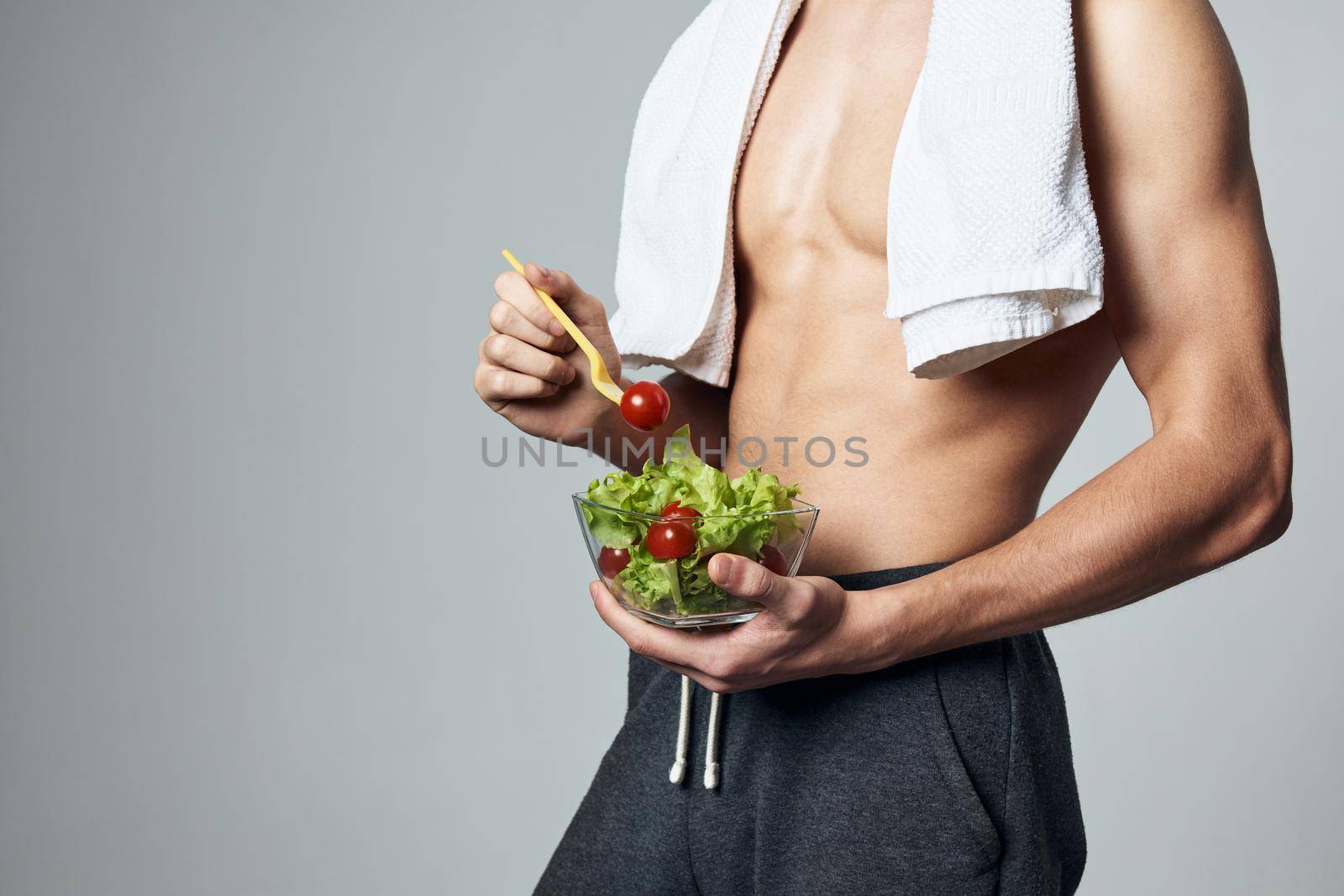 man with white towel on his shoulders pumped up torso carioca salad close-up workout. High quality photo