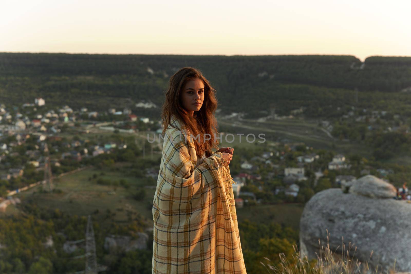 Women in nature mountain with a plaid on the shoulders and the village in the background. High quality photo