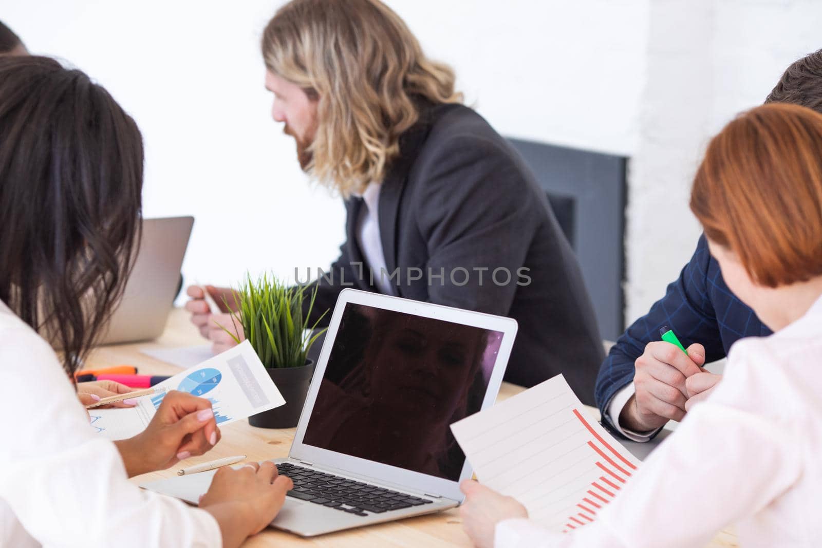 Diverse executive business people team discussing work results at meeting, multiracial businessmen talking analyzing financial statistics report sitting together in modern office