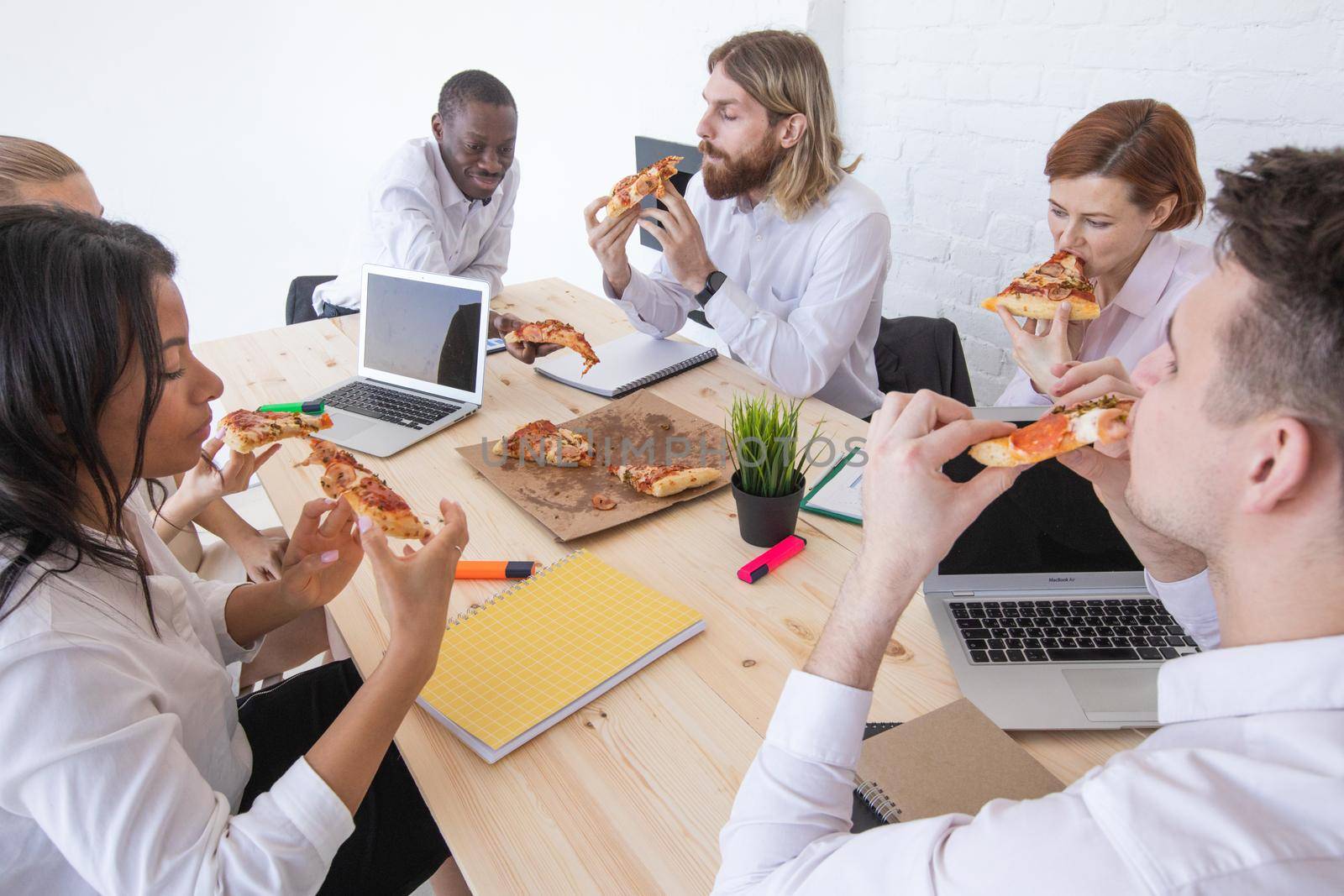 Business people eating pizza in office by ALotOfPeople