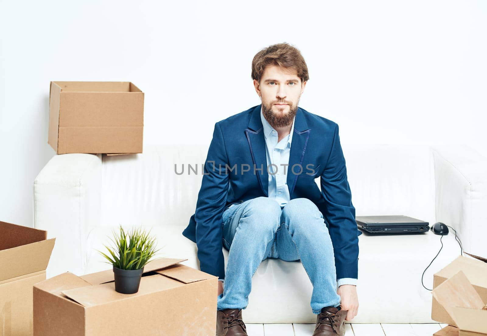 A man sits on the couch next to boxes unpacking a new moving location. High quality photo