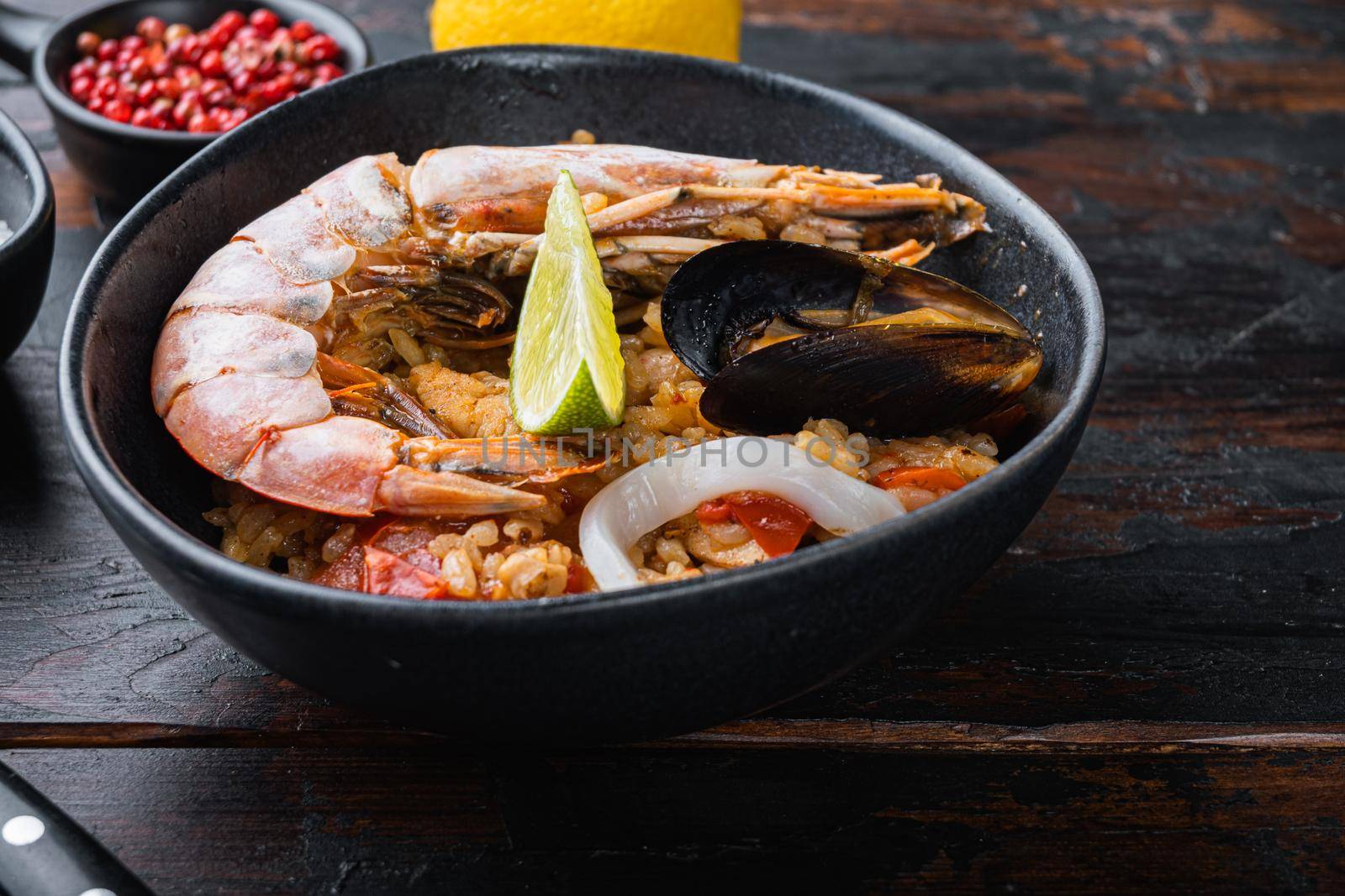 Sea food specialties paella in bowl on old dark wooden table by Ilianesolenyi