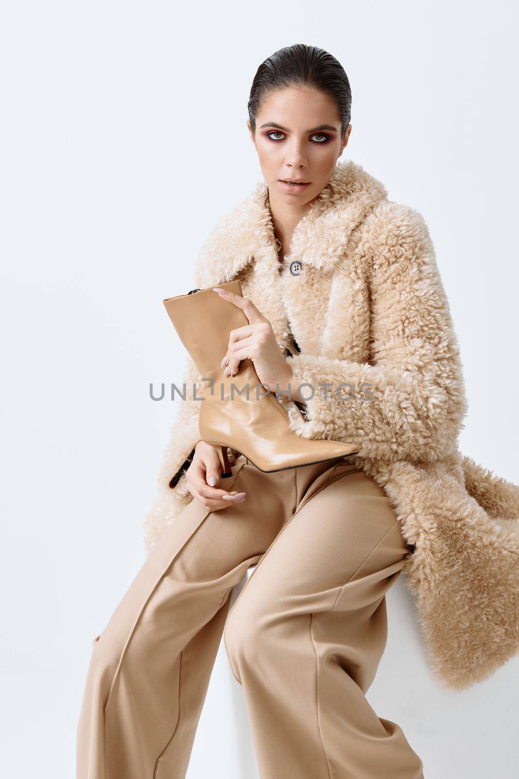 woman in fashionable autumn clothes with shoes in hands posing light background. High quality photo